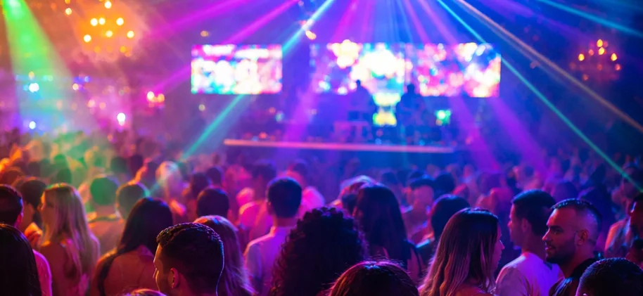 Vibrant nightclub scene with colorful lights and people enjoying drinks.