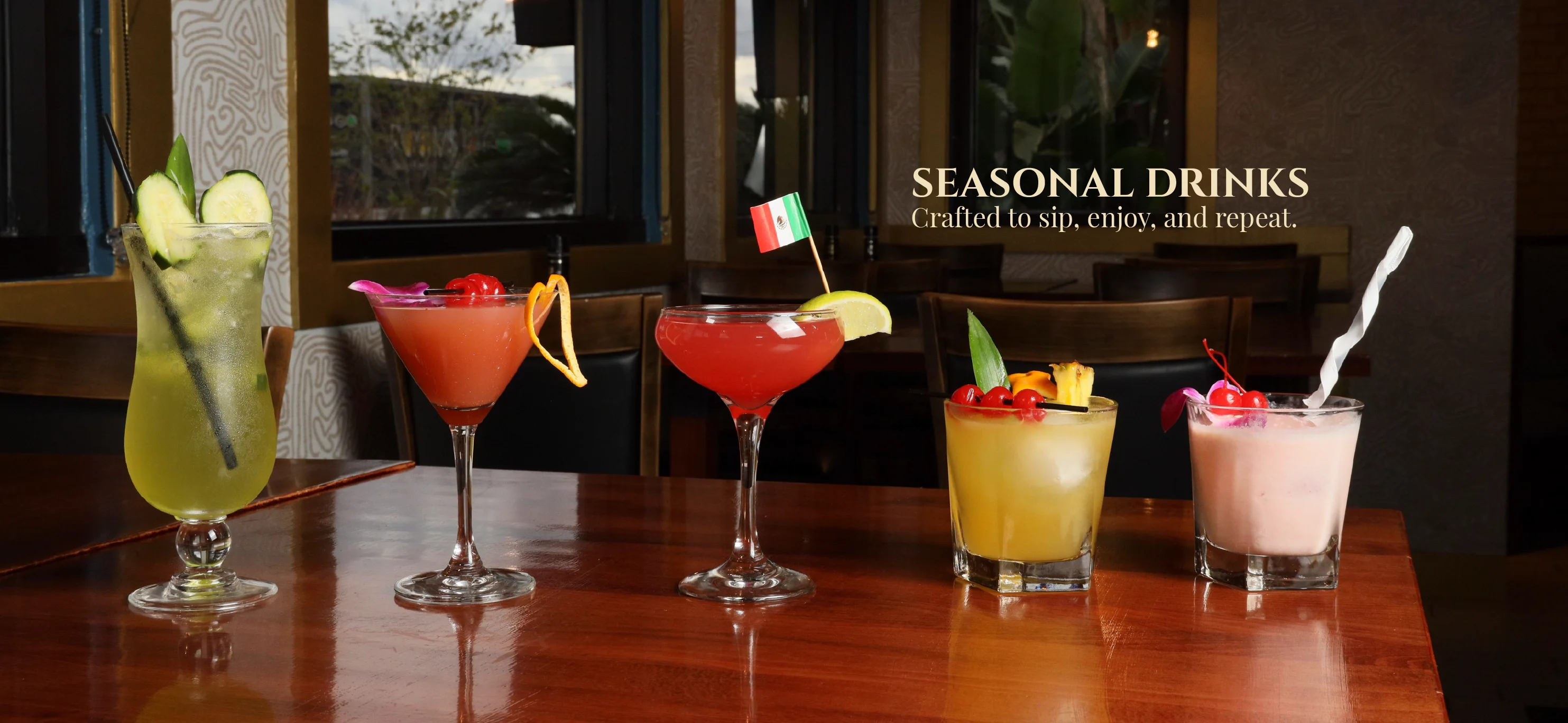 Four colorful seasonal cocktails on a wooden table.