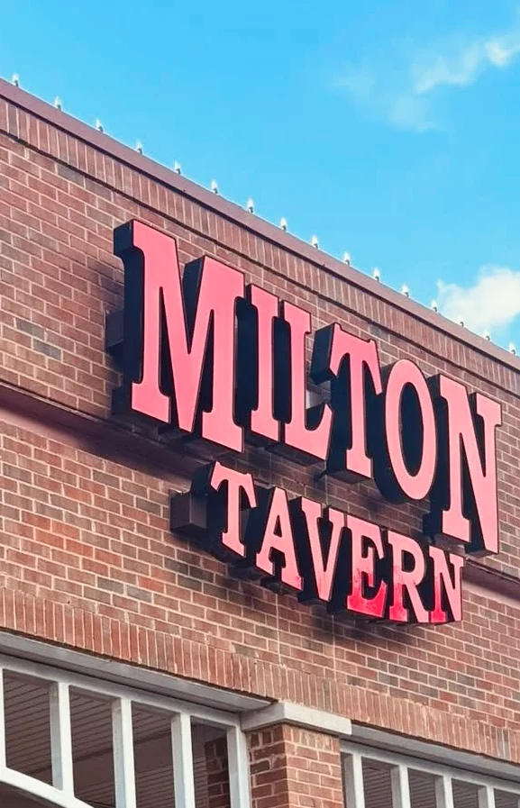 Exterior view of Milton Tavern with outdoor seating and American flag