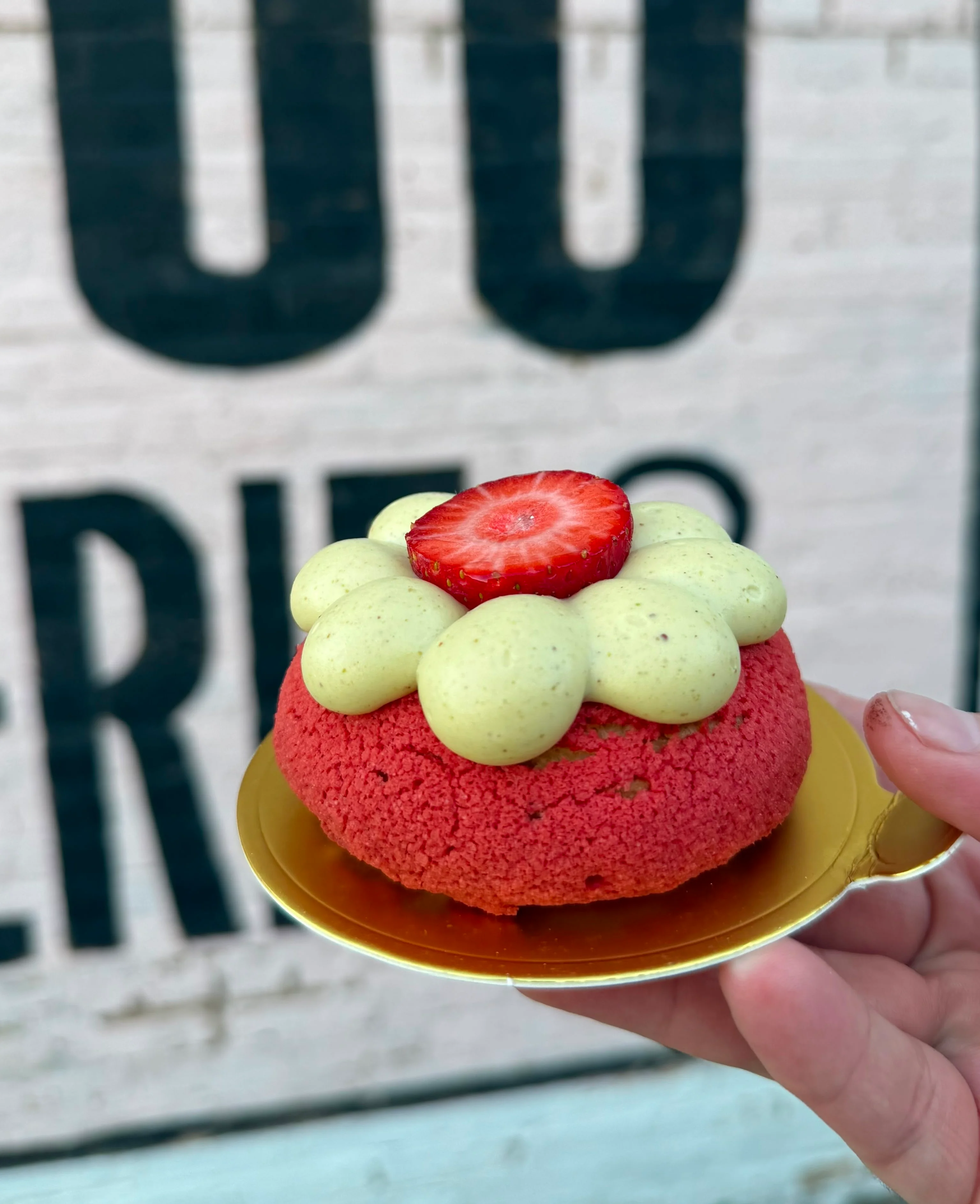 Heart-shaped Raspberry Blush St-Honoré on a plate with “xoxo,” surrounded by Lego flowers and a bottle of wine, creating a warm, cozy Valentine’s Day café vibe