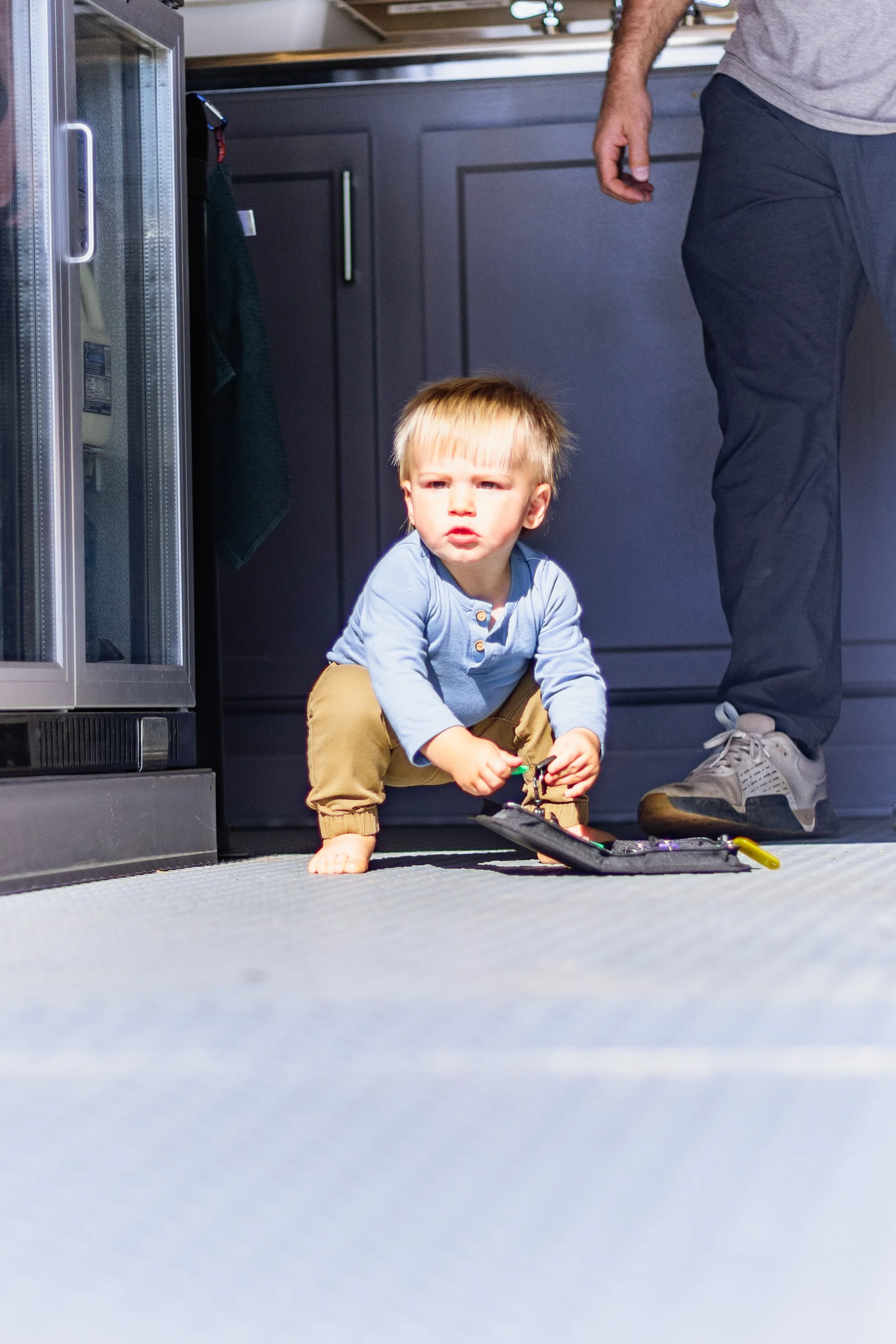 Toddler playing on kitchen floor with toys