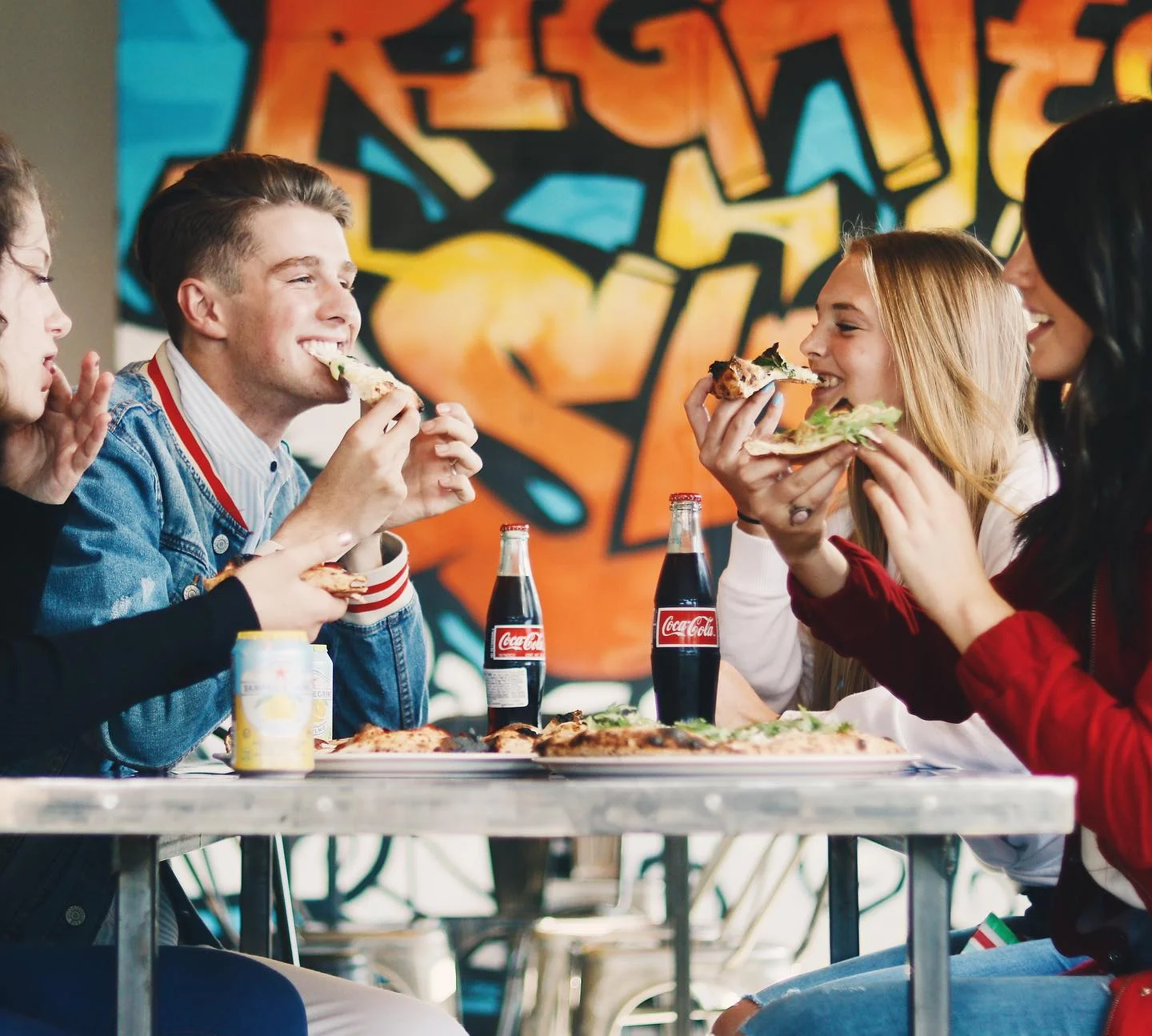 Group enjoying pizza and Coca-Cola in a vibrant restaurant setting