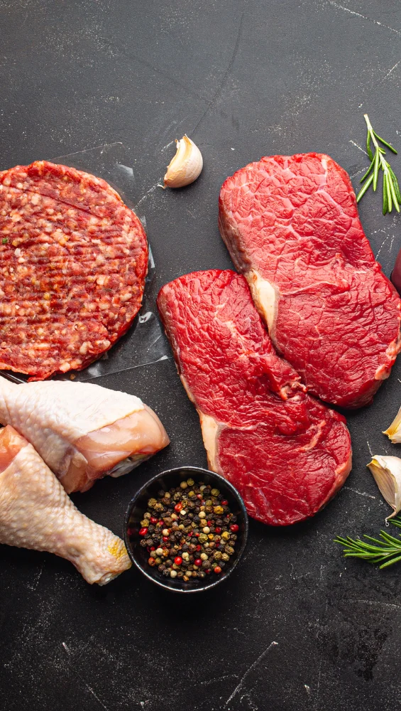 Assorted raw meats for grilling in a rustic kitchen setting