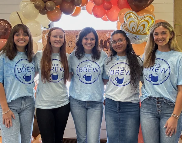 Team members at The Brew coffee shop celebrating with balloons