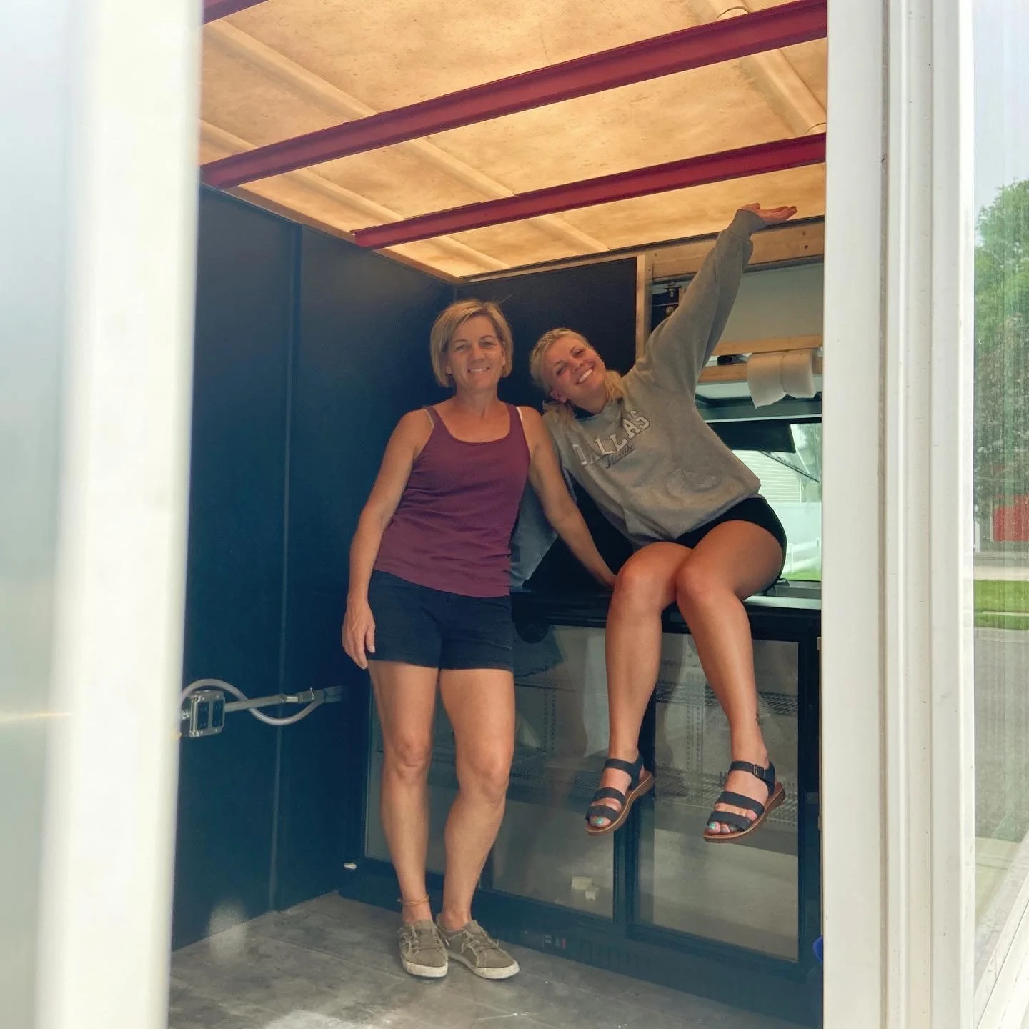 Two women inside a food truck preparing for service