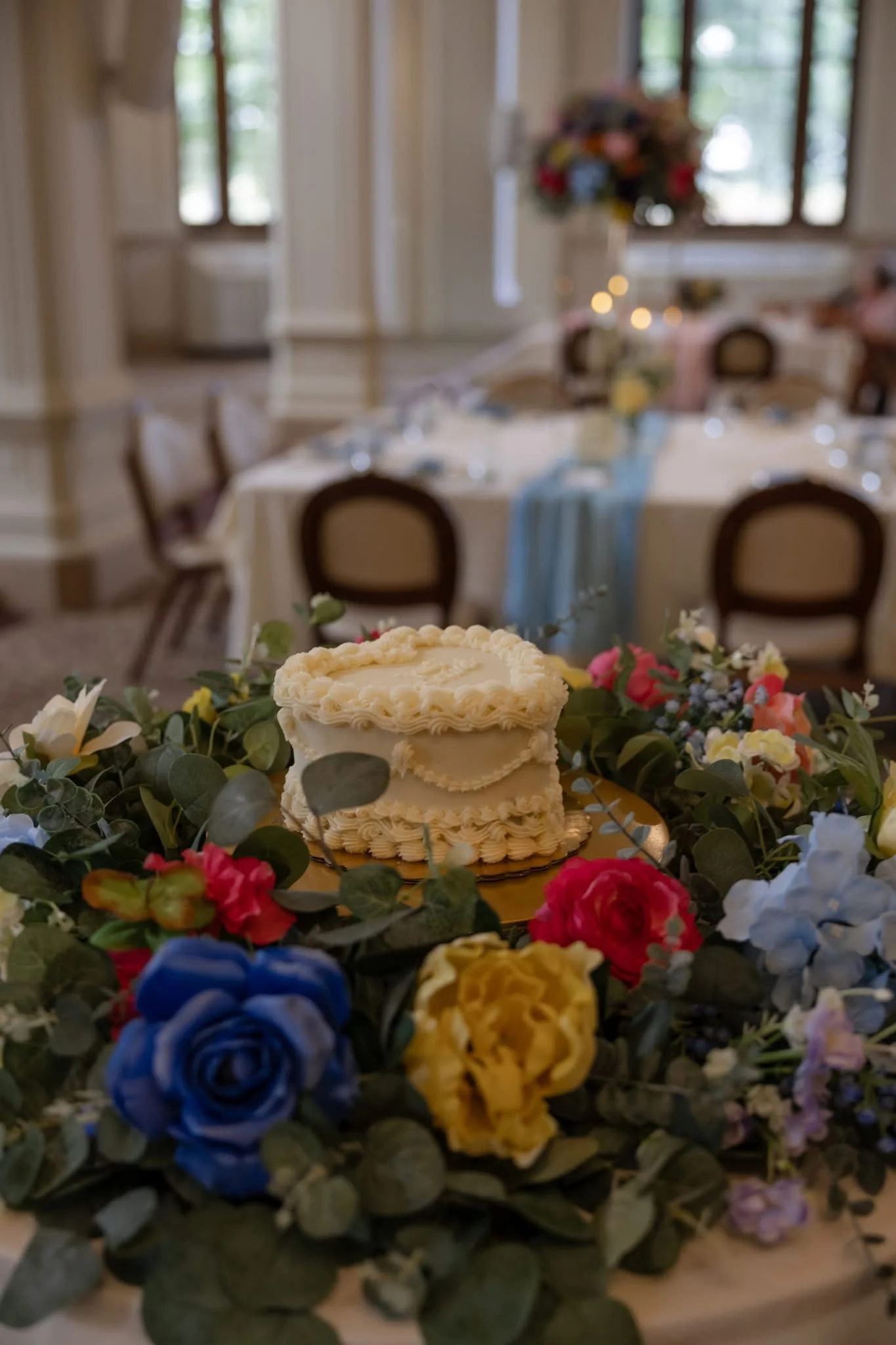 Elegant wedding cake adorned with flowers in a beautifully set dining area