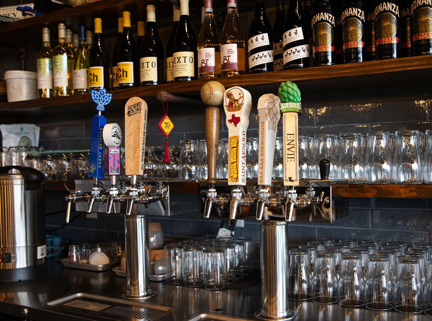 Craft beer taps and wine bottles behind a polished restaurant bar