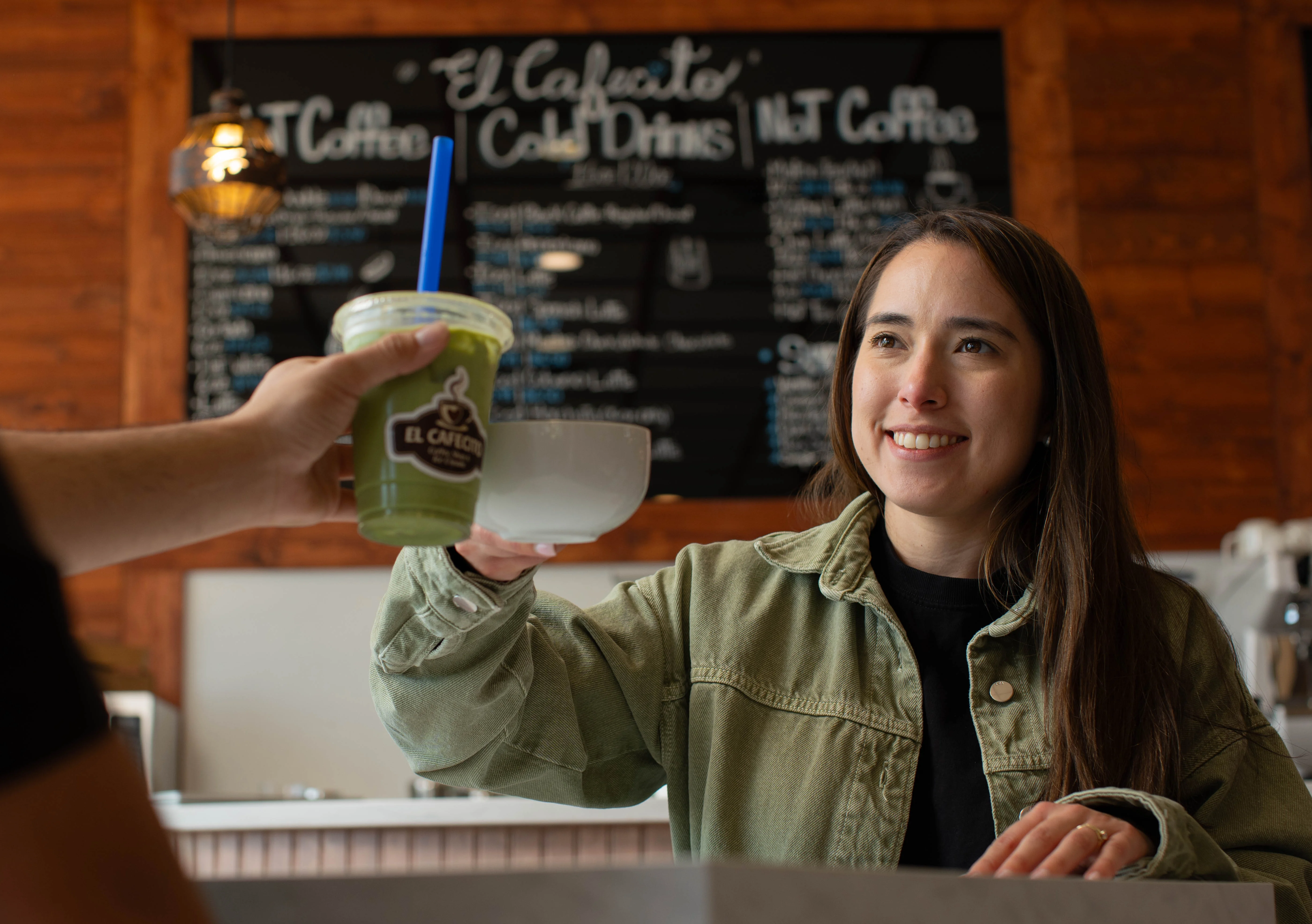 Customer receiving a drink at a coffee shop counter.