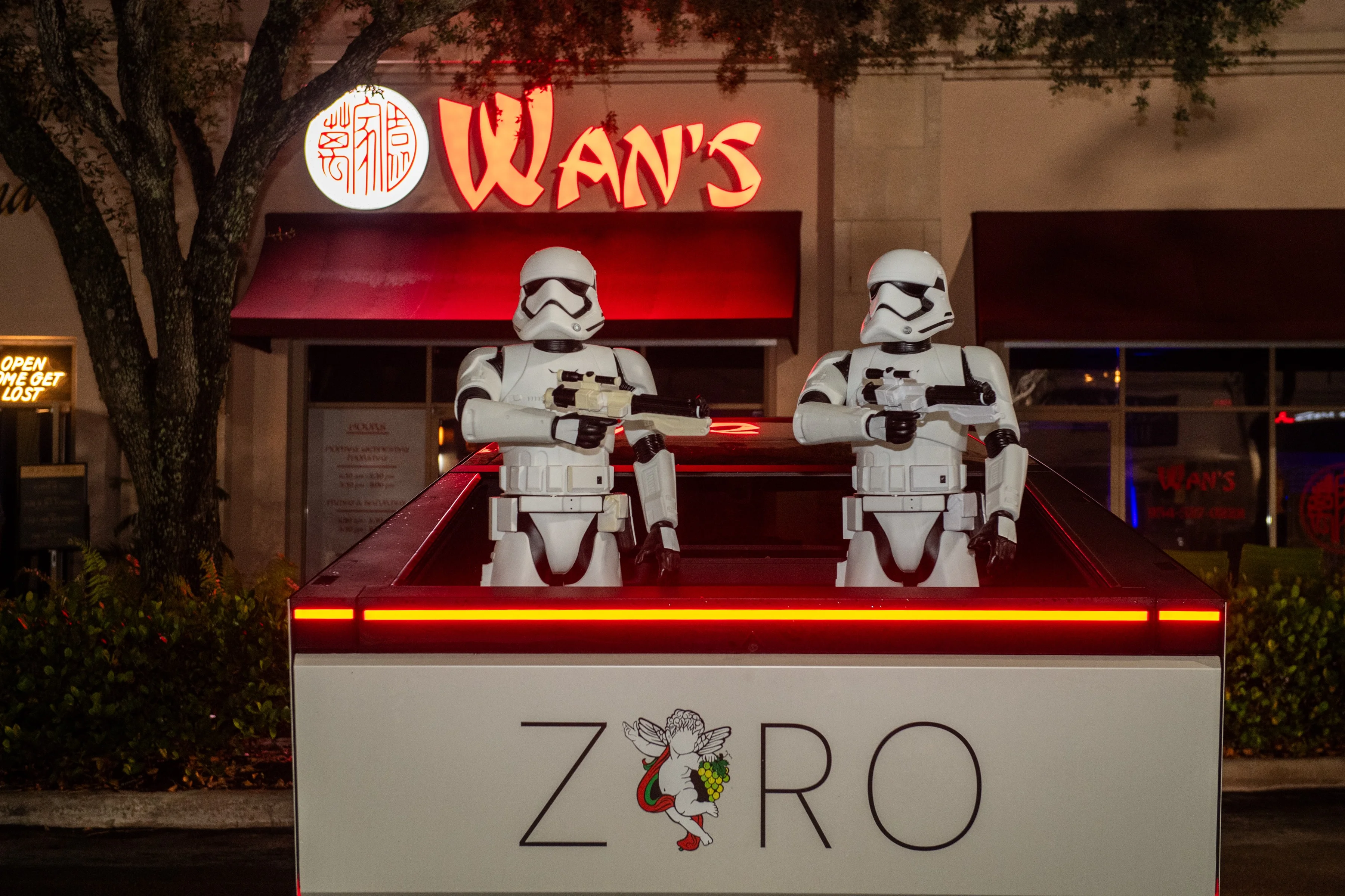 Two stormtrooper figures in a restaurant setting at night.