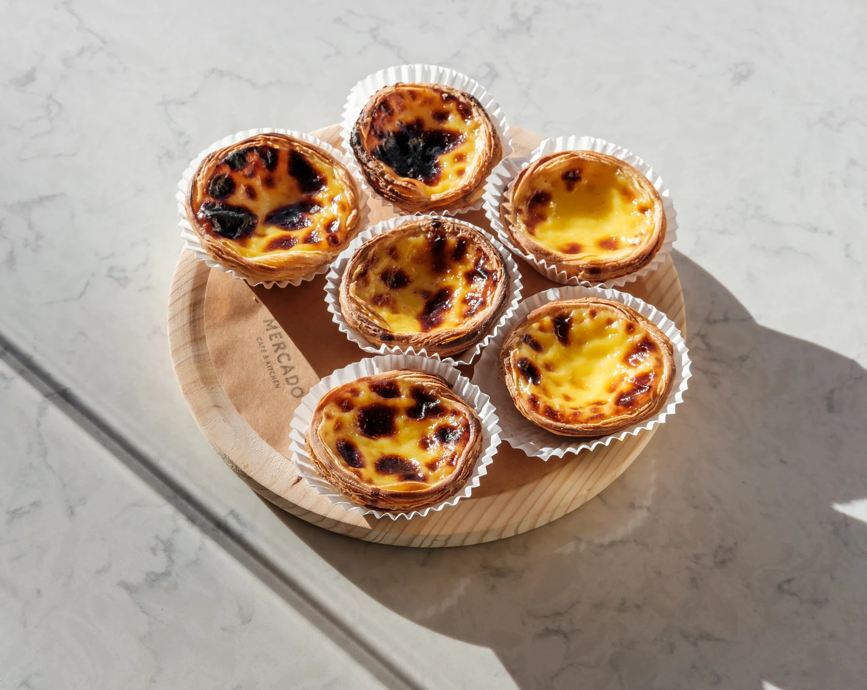 Portuguese pastéis de nata on a wooden platter