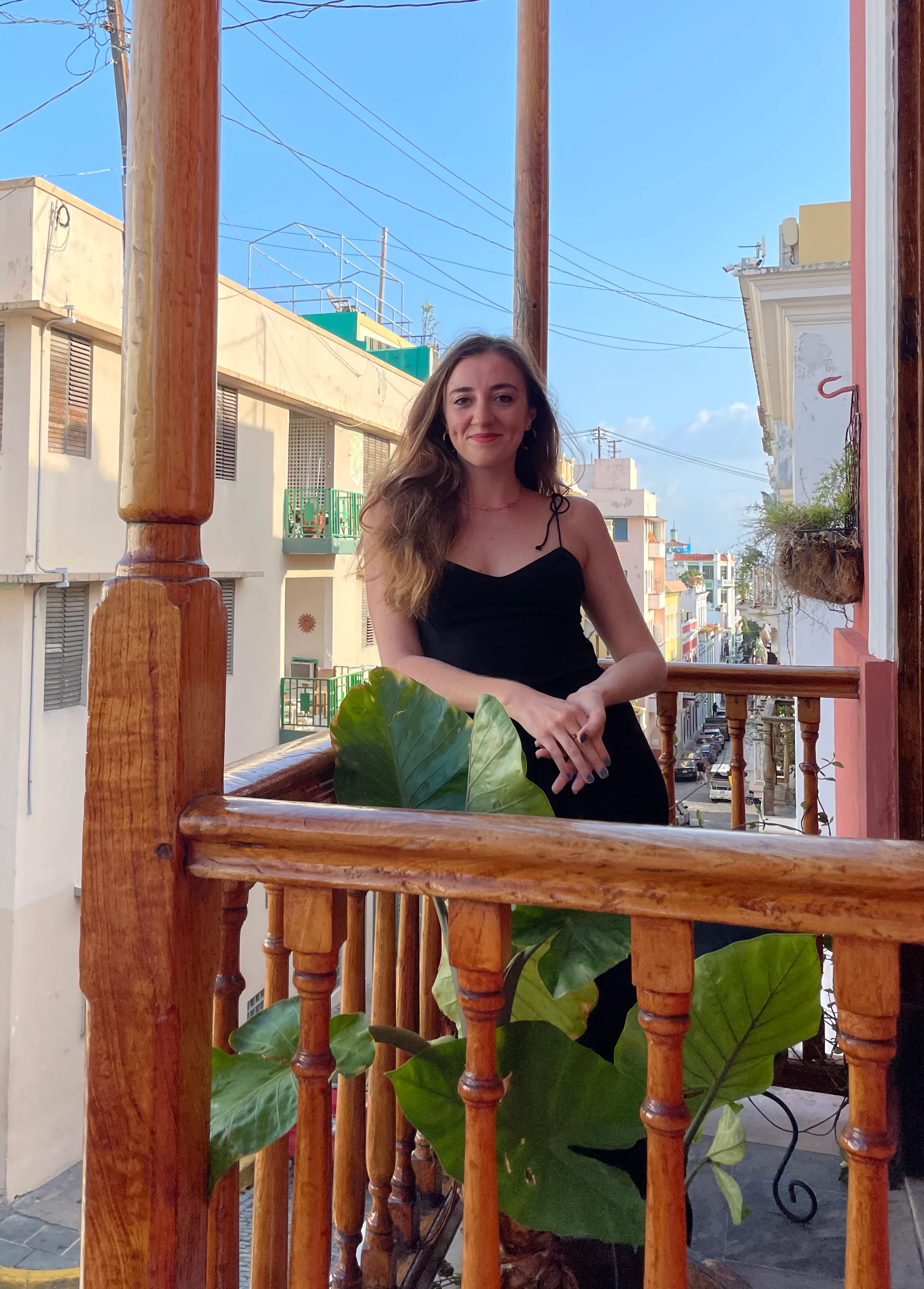 Woman enjoying a sunny balcony view in a vibrant urban setting