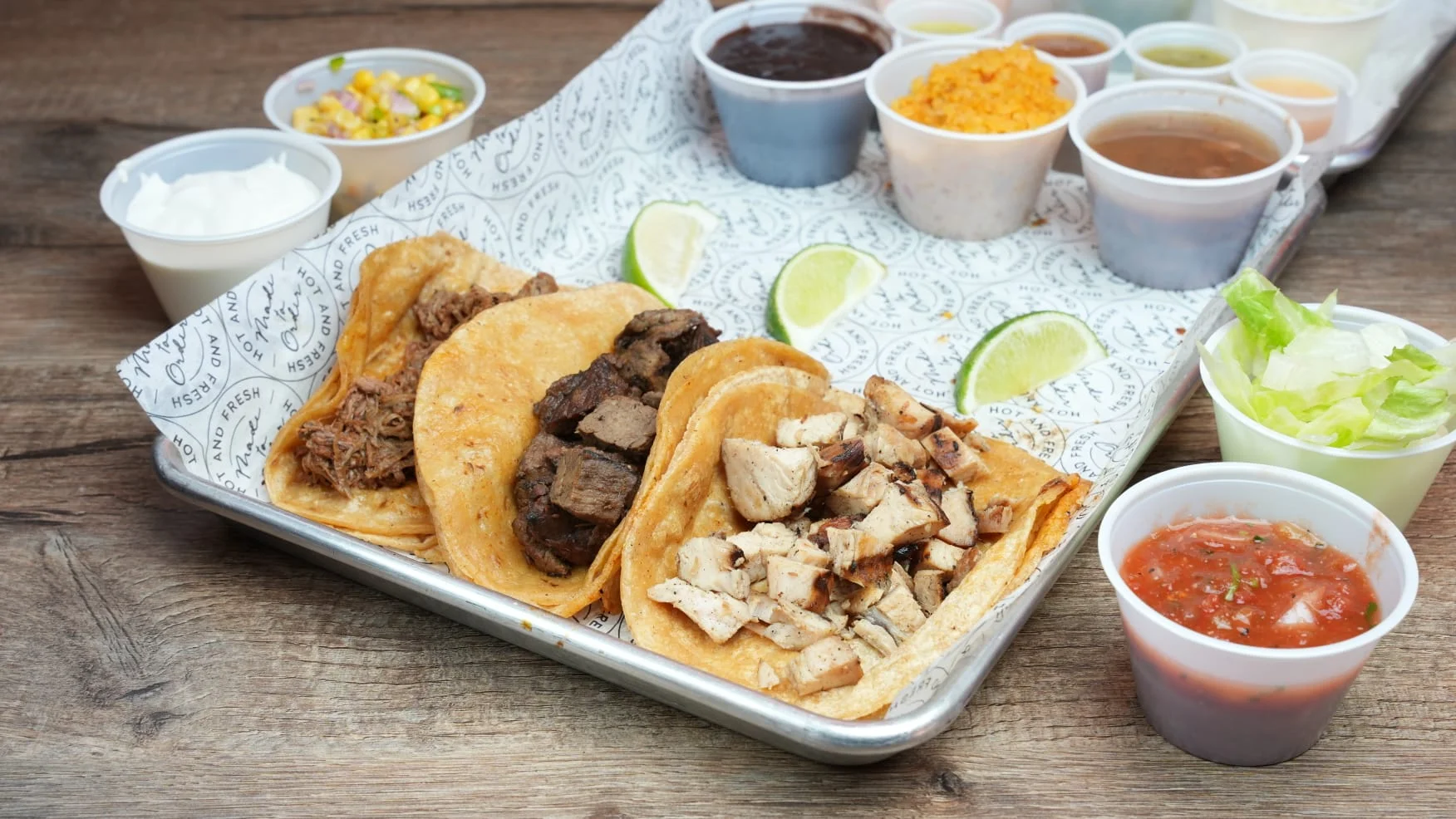 Assorted tacos with beef and chicken served with lime wedges