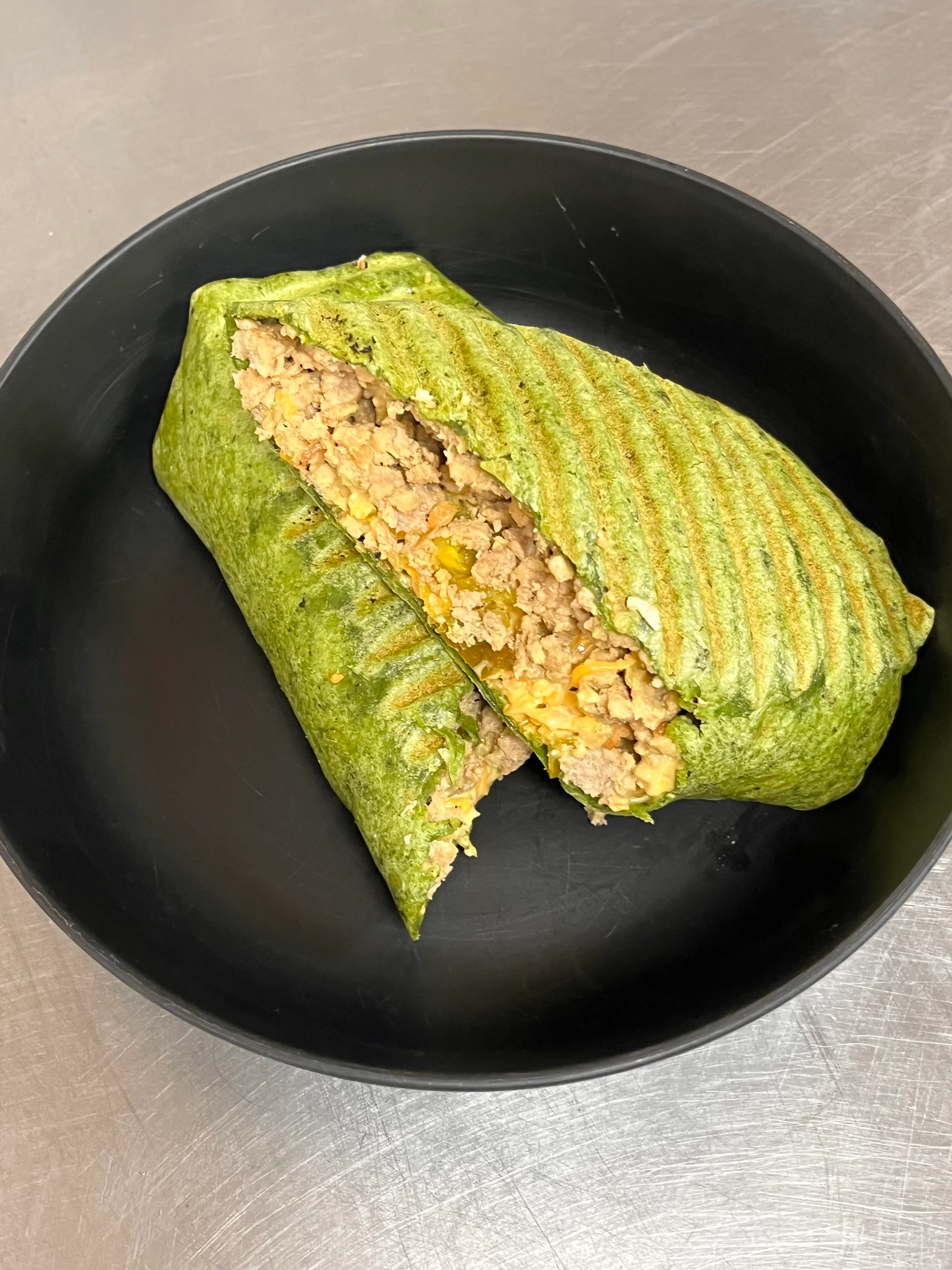 Grilled spinach wrap filled with seasoned meat, a fusion dish