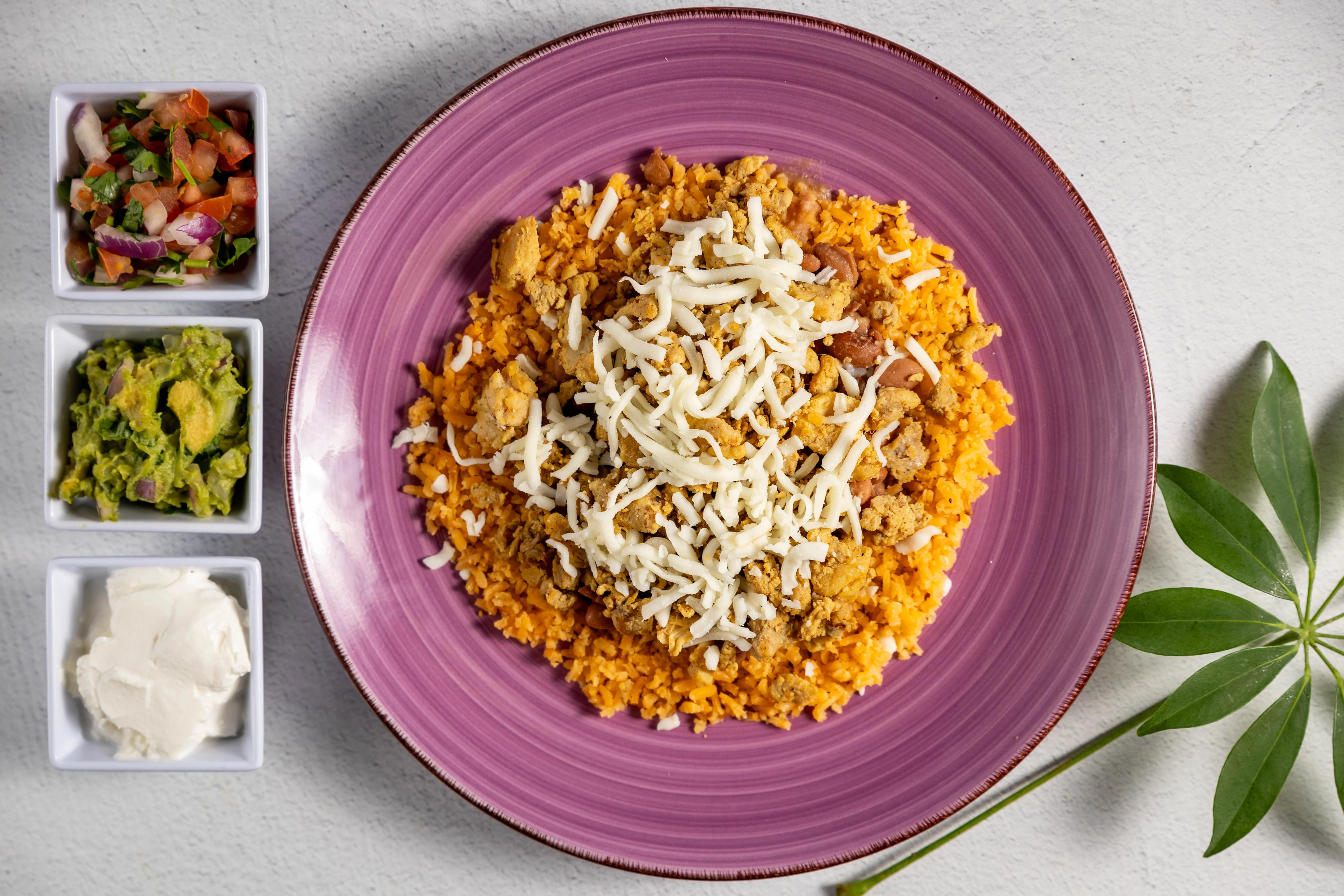 Top view of a colorful bowl with pollo, vegetables, and purple plate.