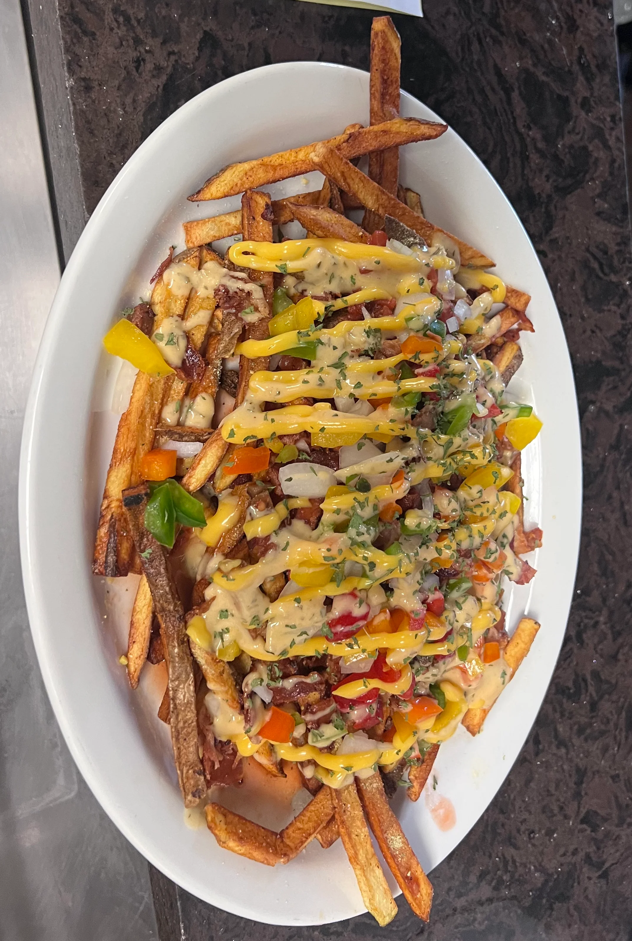 Loaded fries topped with cheese and colorful vegetables