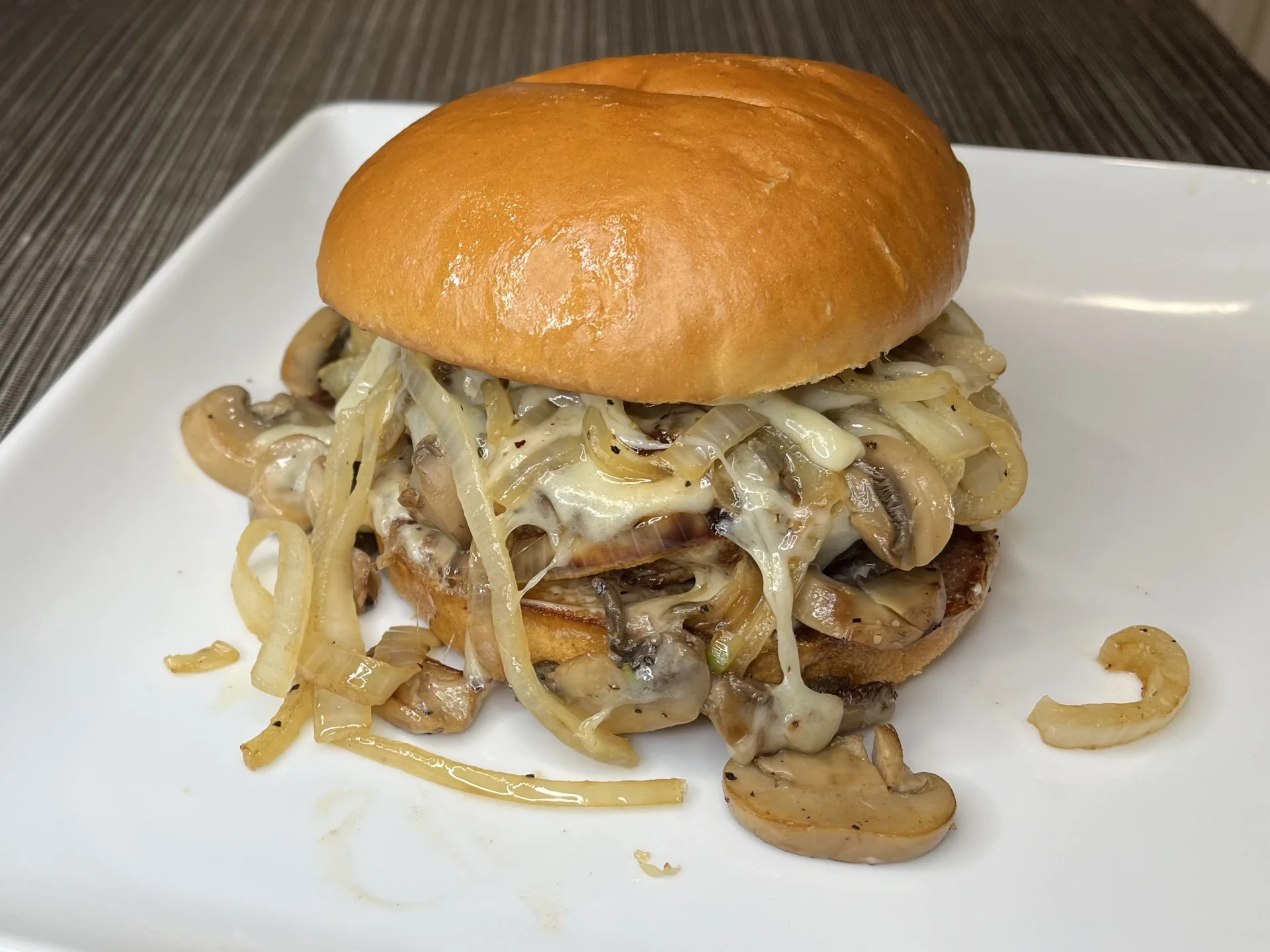 Mushroom and onion cheesesteak sandwich on a toasted bun