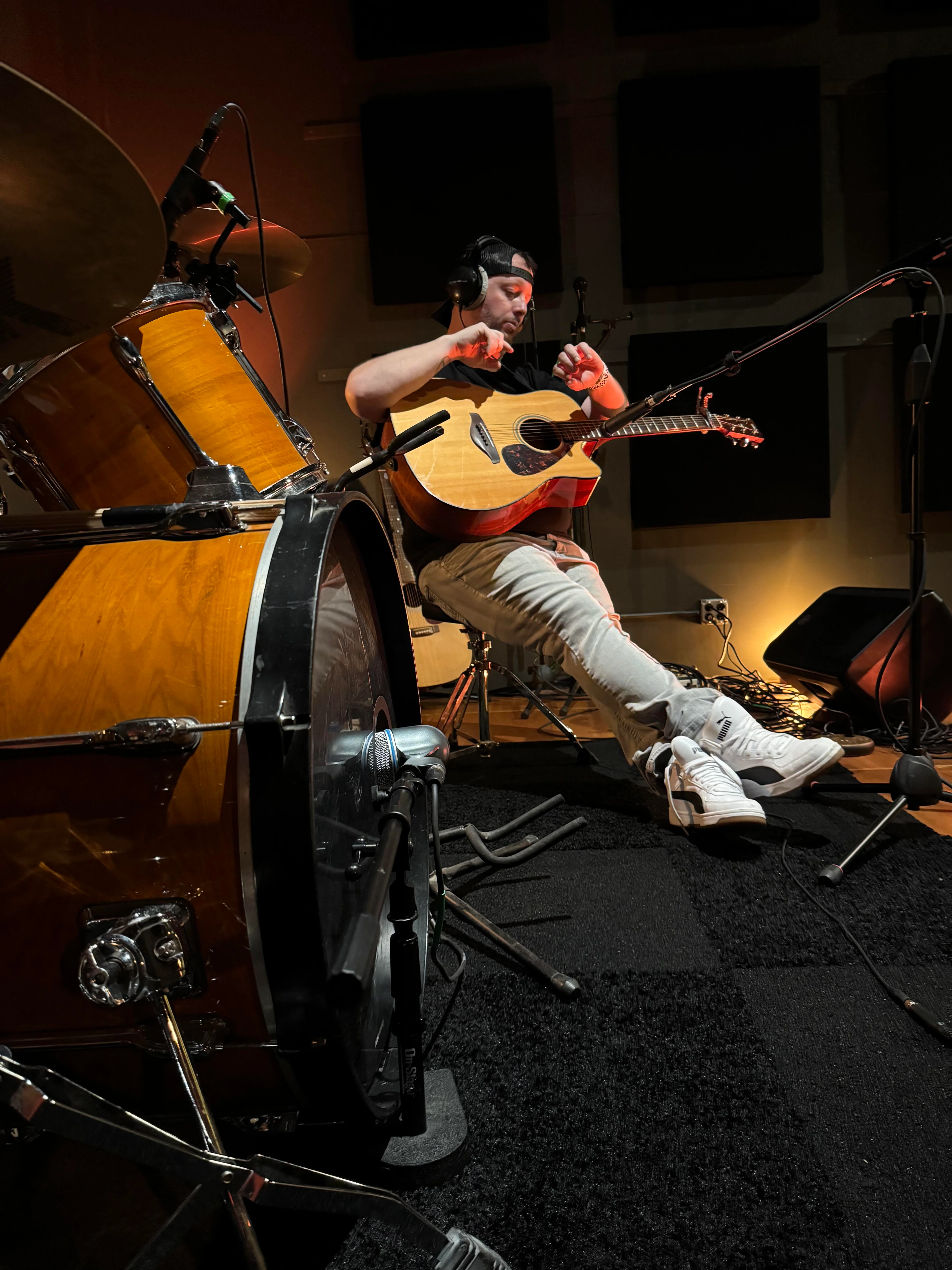 Musician playing acoustic guitar in a recording studio