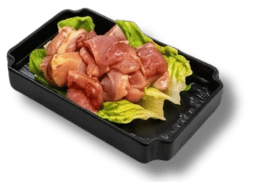 Raw chicken pieces on lettuce in a black tray