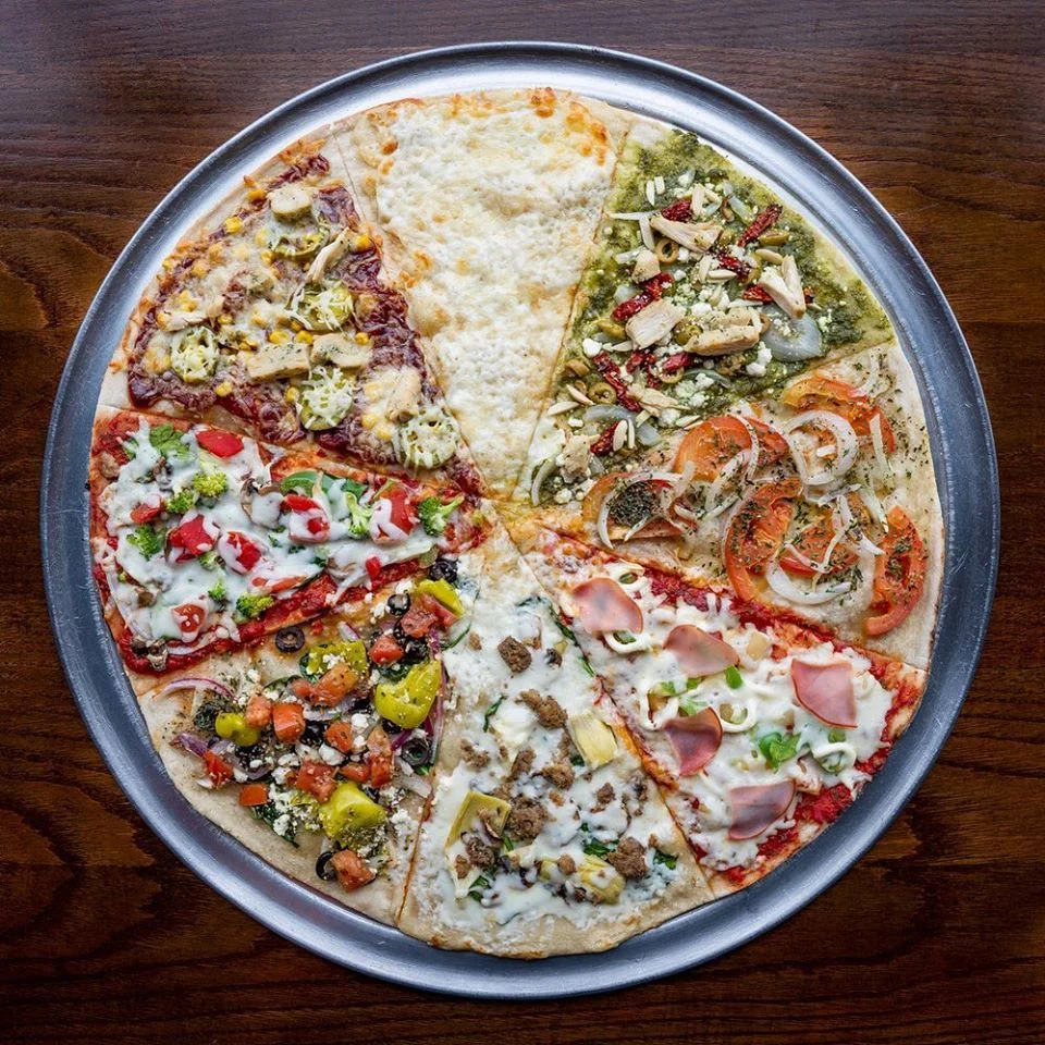Assorted gourmet pizza slices on a metal tray