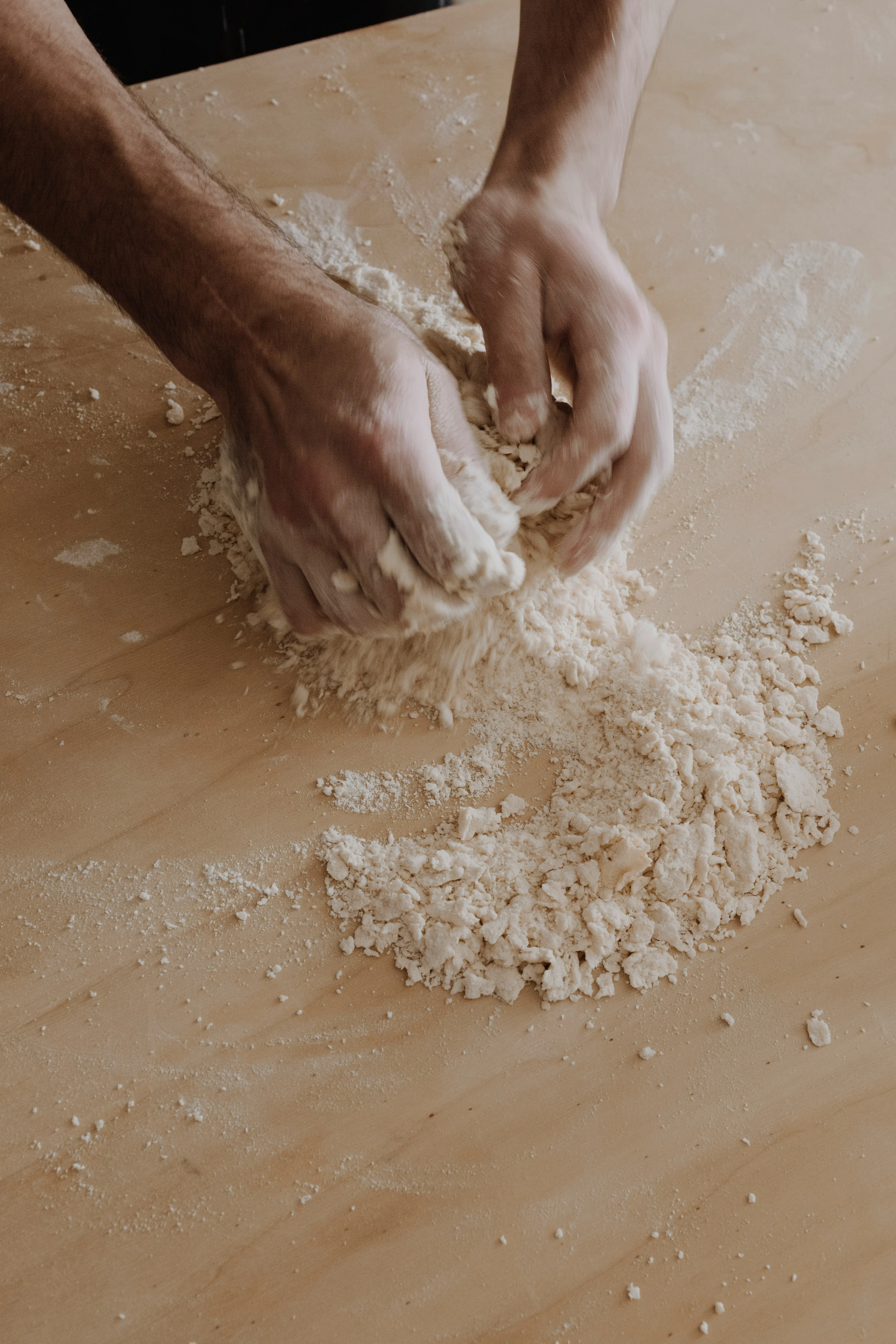 Baker kneading dough on a wooden surface