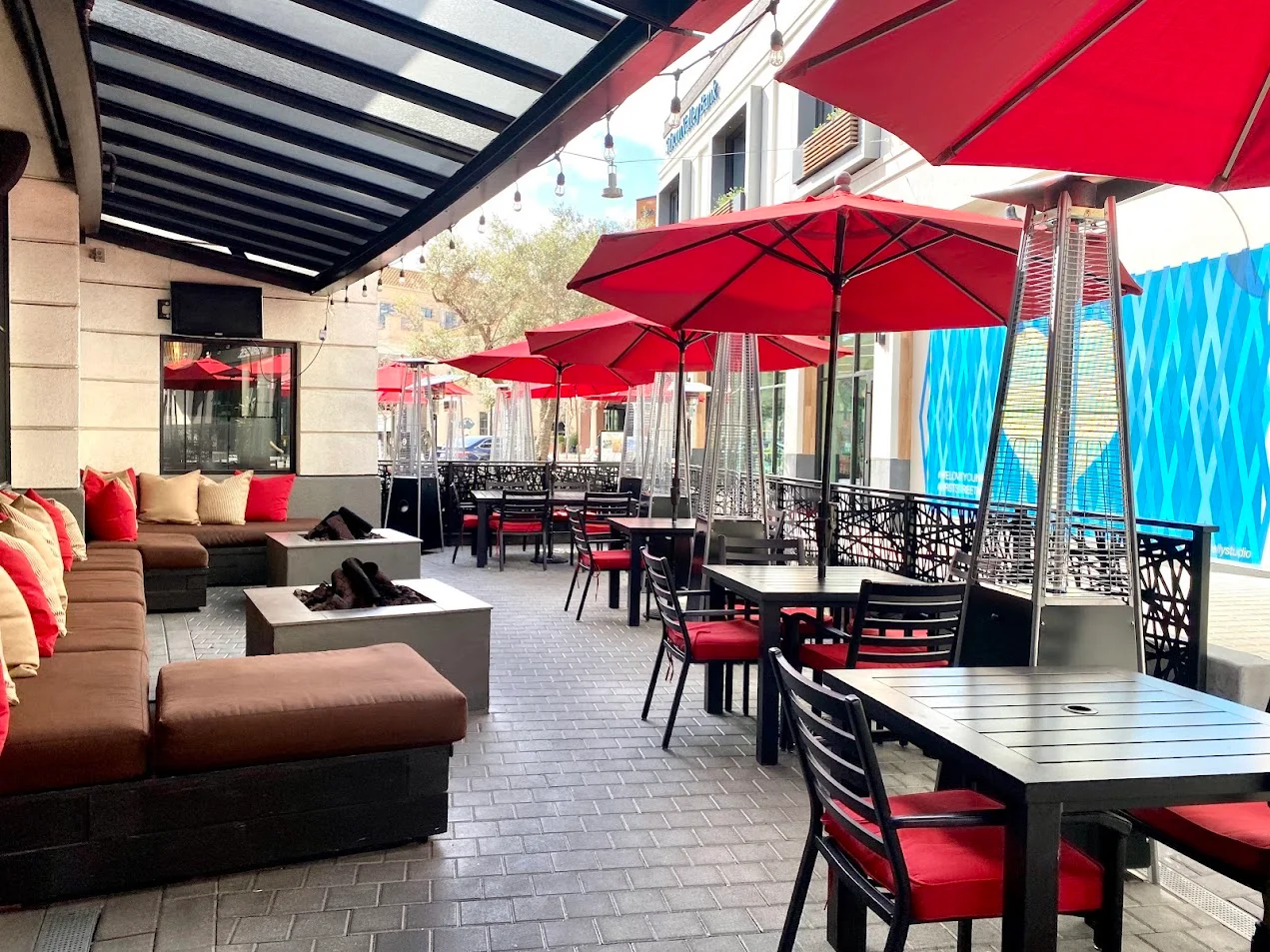 Outdoor dining area with red umbrellas and cozy seating