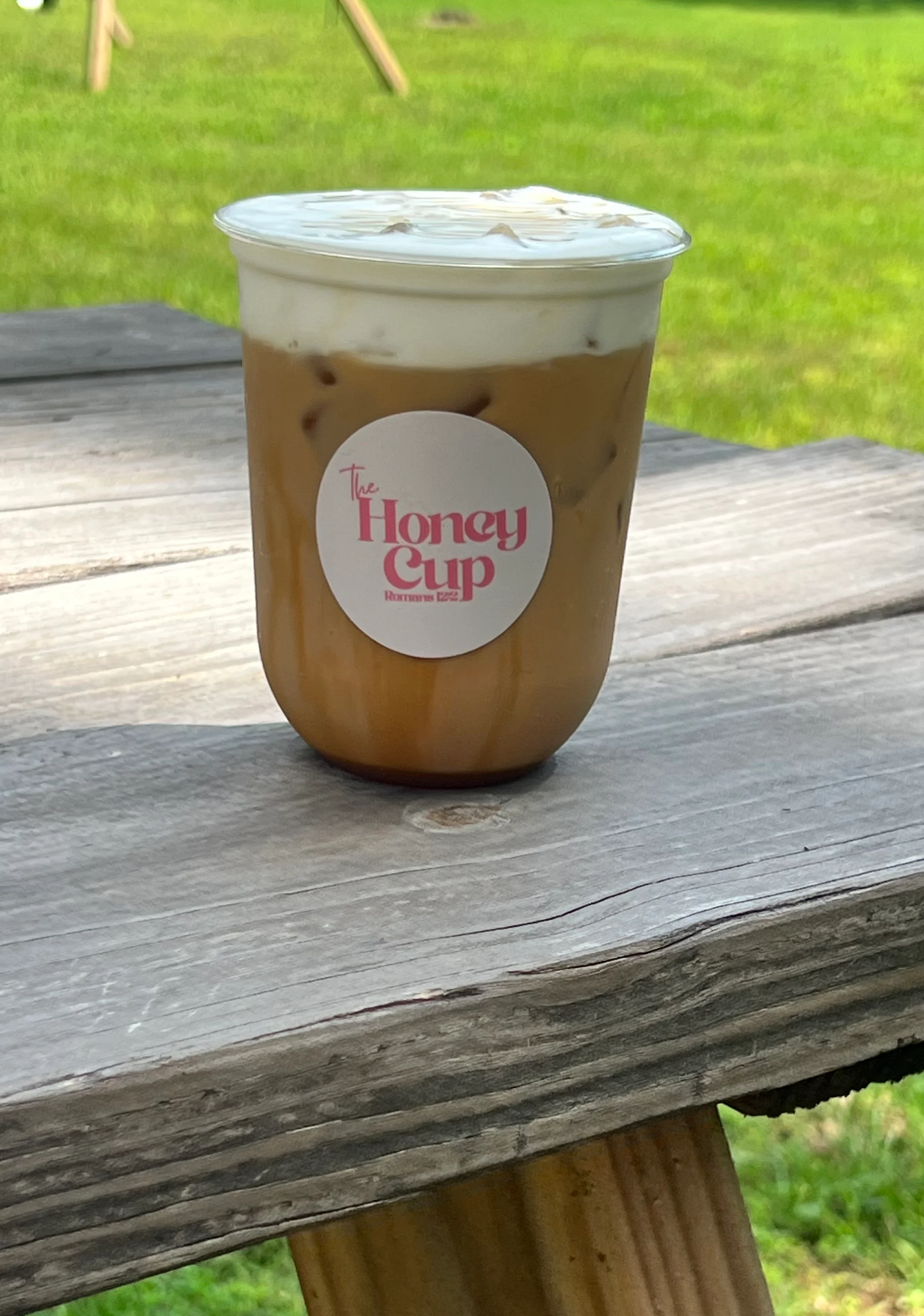 A green beverage with pink foam in a cup from The Honey Cup.