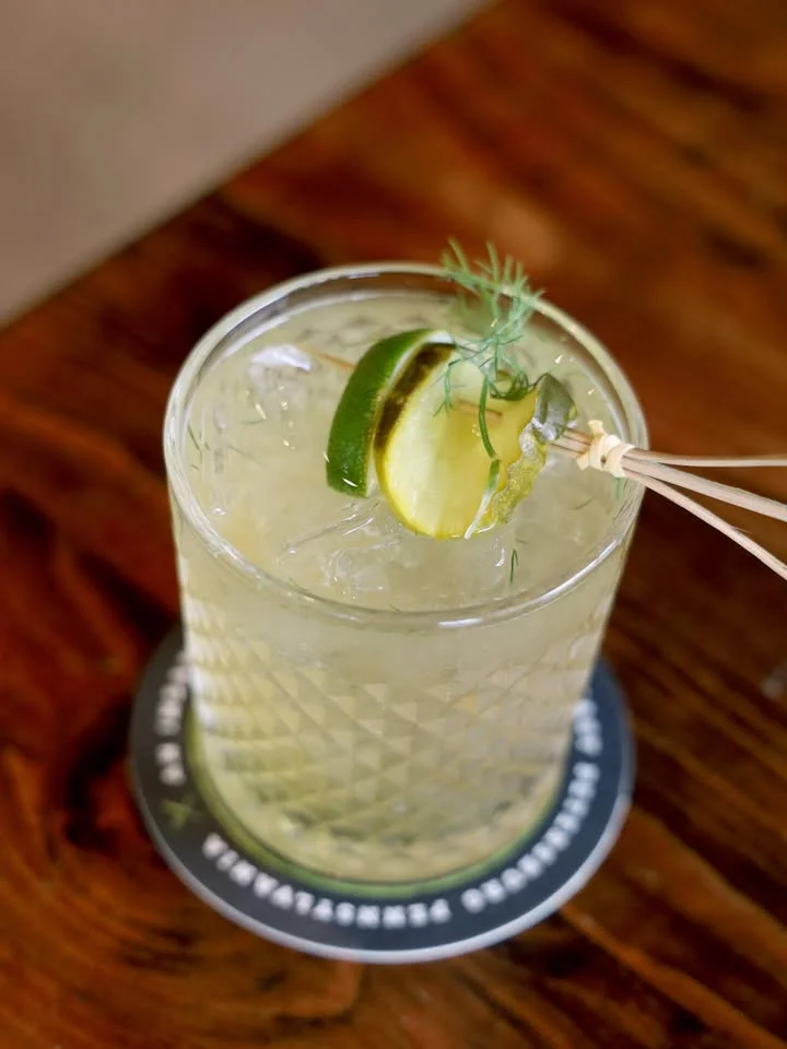 Refreshing cocktail garnished with lime and herbs