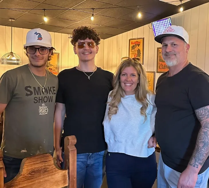 Four smiling guests posing inside a warmly lit restaurant