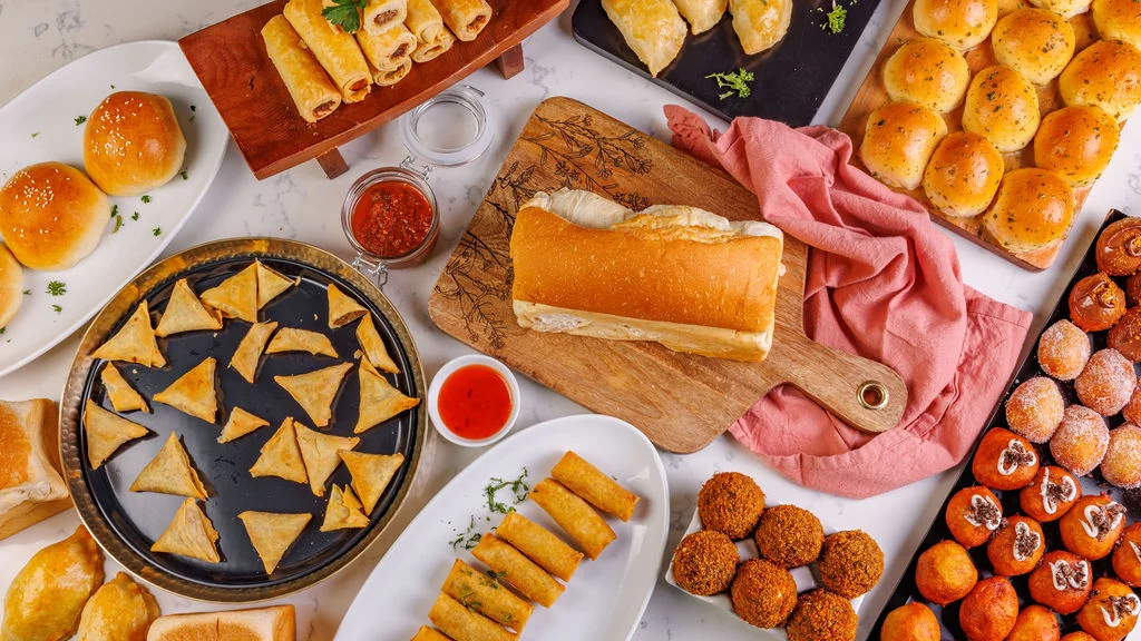 Assorted Indian snacks including samosas and rolls on a table