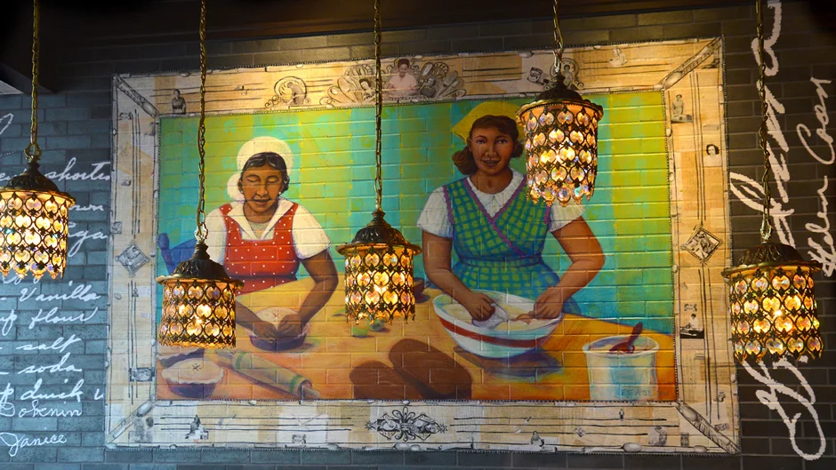 Colorful mural of women preparing traditional food in a cozy restaurant