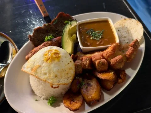 Traditional Colombian bandeja paisa with rice, fried egg, plantains, avocado and chicharrón