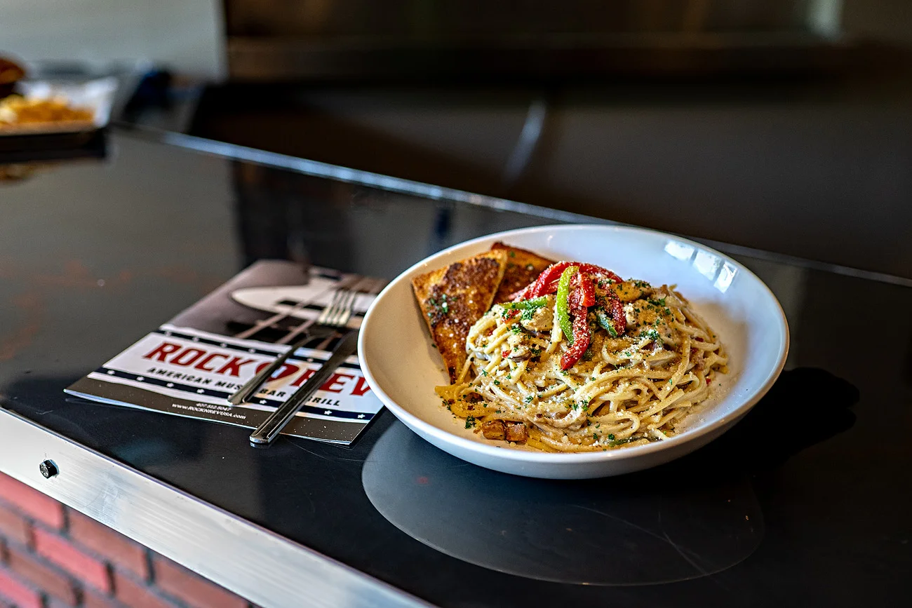Creamy spaghetti carbonara garnished with red peppers and served with toasted bread