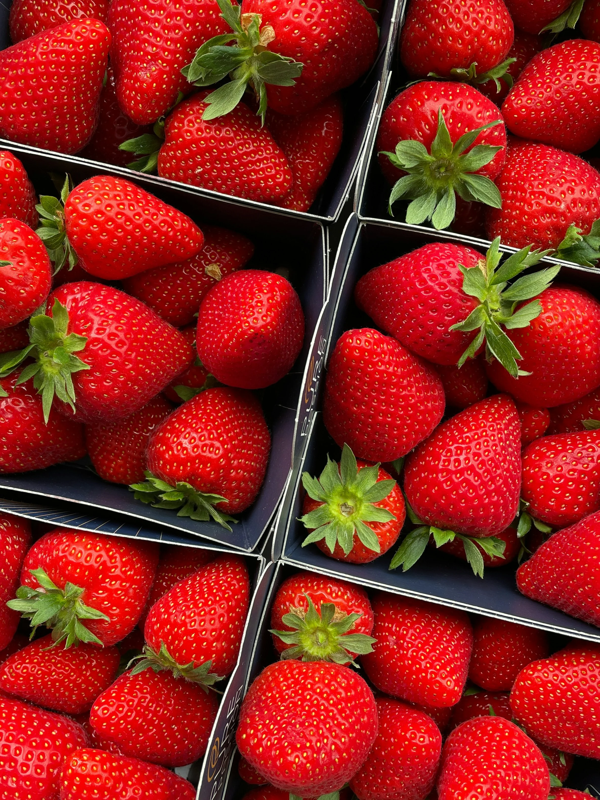 Fresh strawberries in black boxes at a market