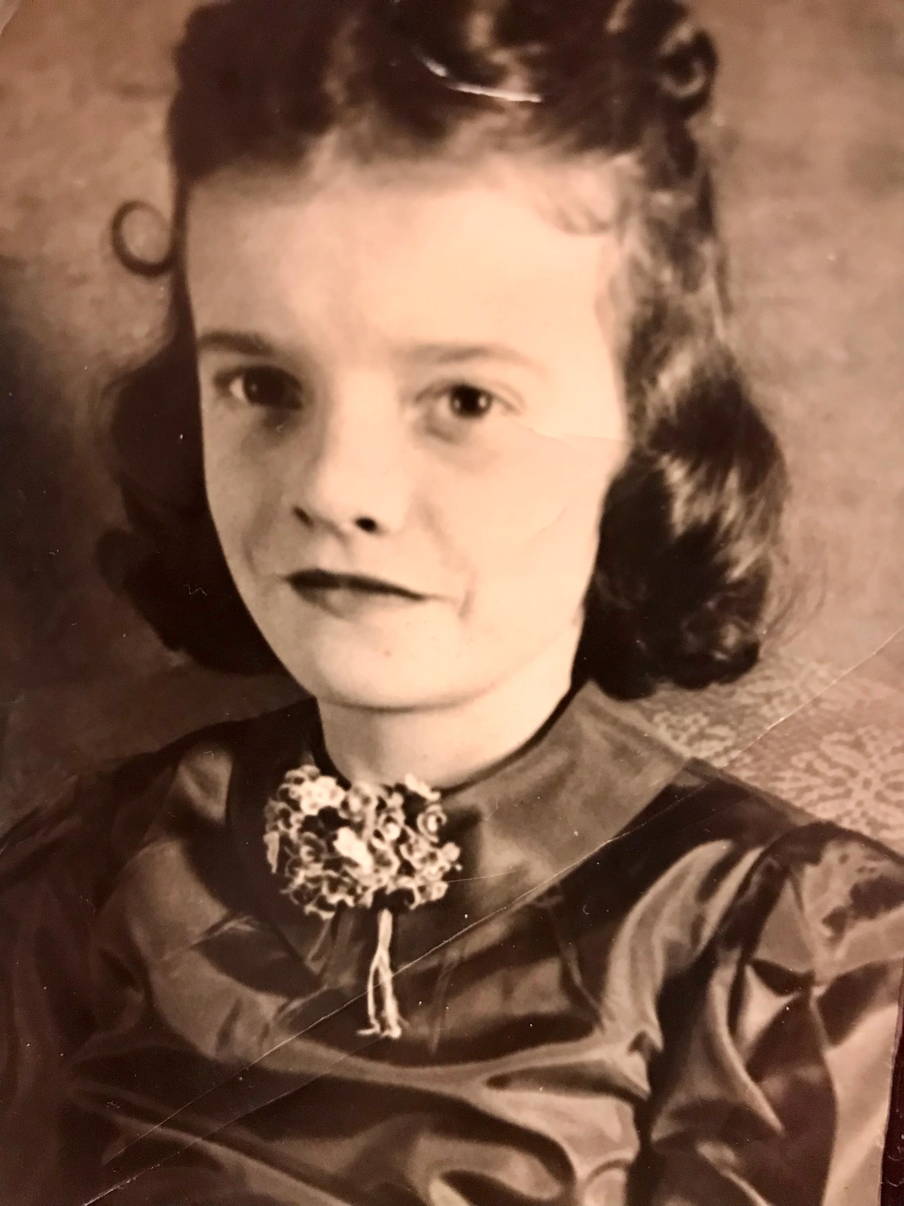 Vintage portrait of a young girl with curly hair and a floral brooch