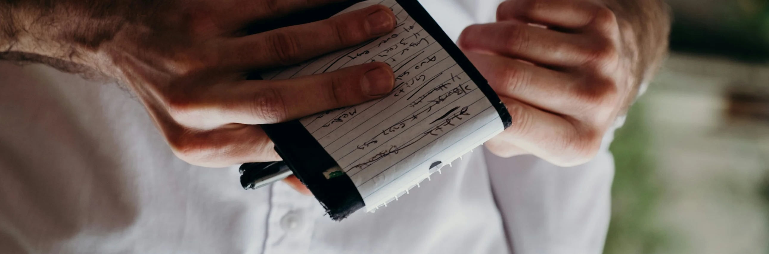 A server holding a notepad and pen, taking orders from a customer, with partially visible menus in the foreground.