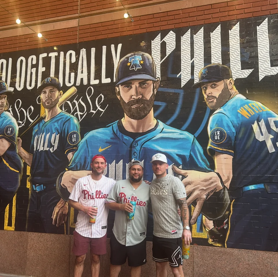 A trio of people in front of a baseball mural