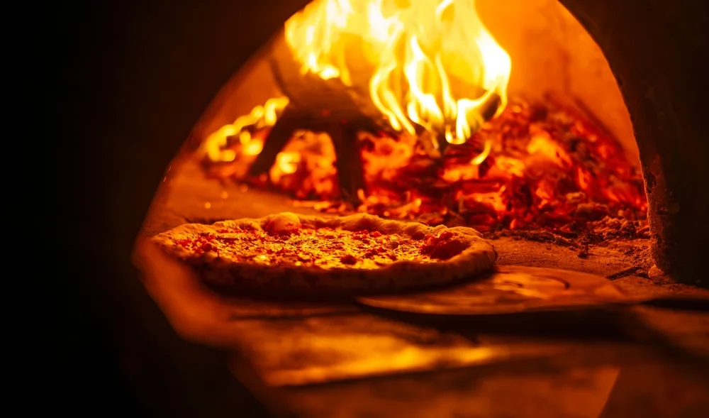 Margherita pizza baking in a wood-fired oven