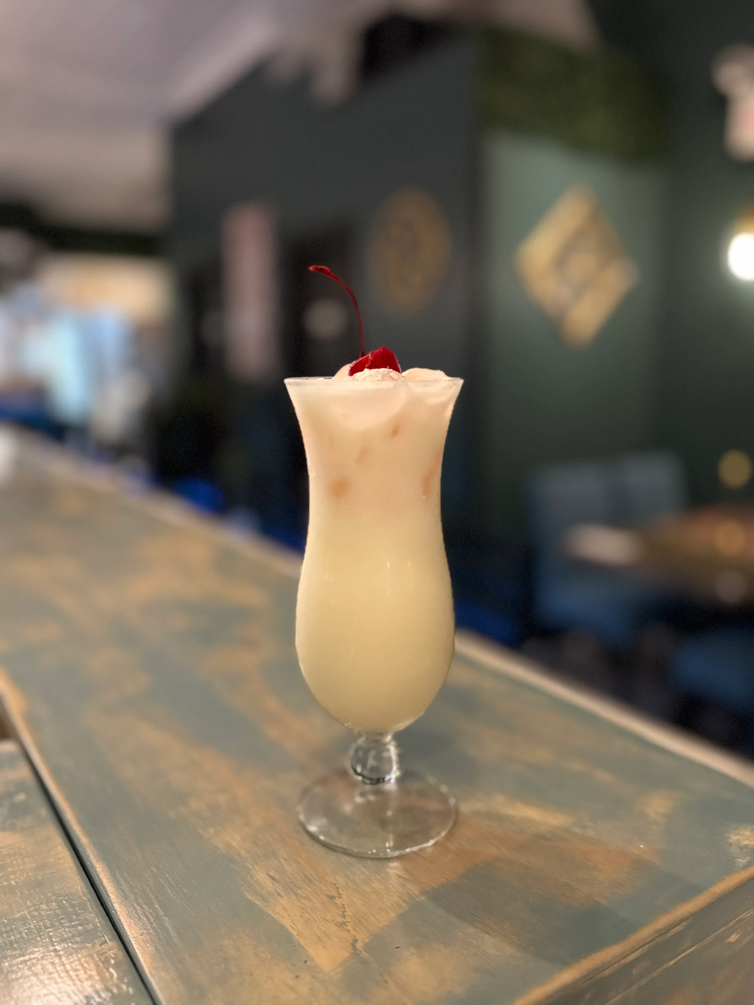 Creamy cocktail topped with whipped cream and a cherry