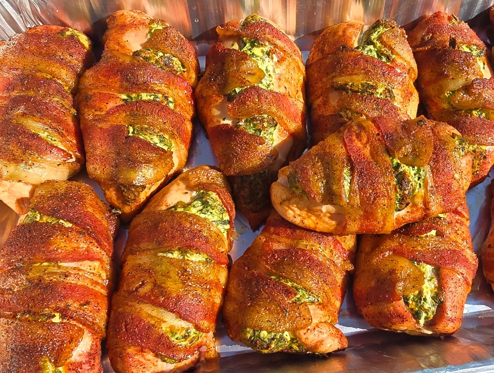 Bacon-wrapped stuffed chicken breasts with seasoning on a tray.