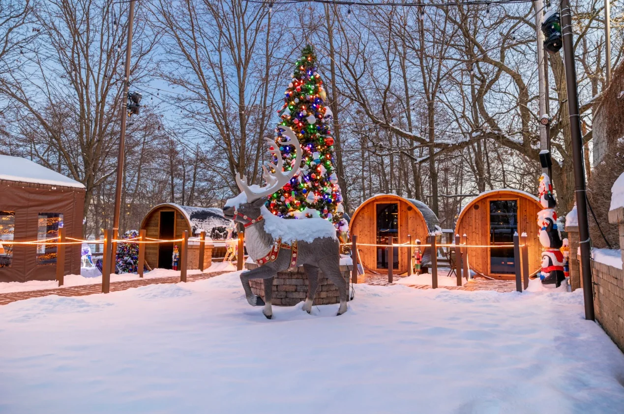Festive winter scene with a decorated Christmas tree and reindeer statue
