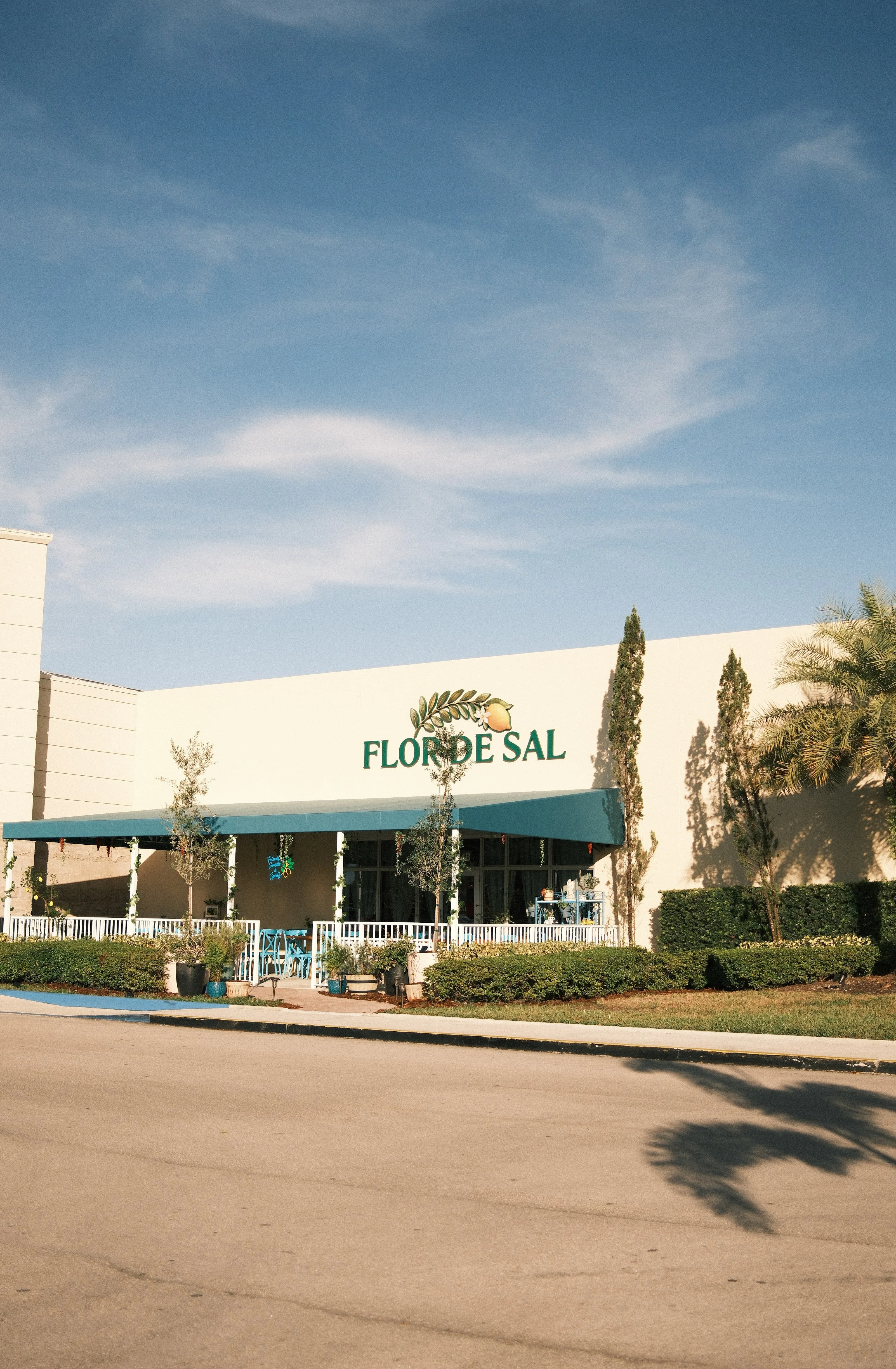 Exterior view of Flor de Sal restaurant with blue awning and greenery