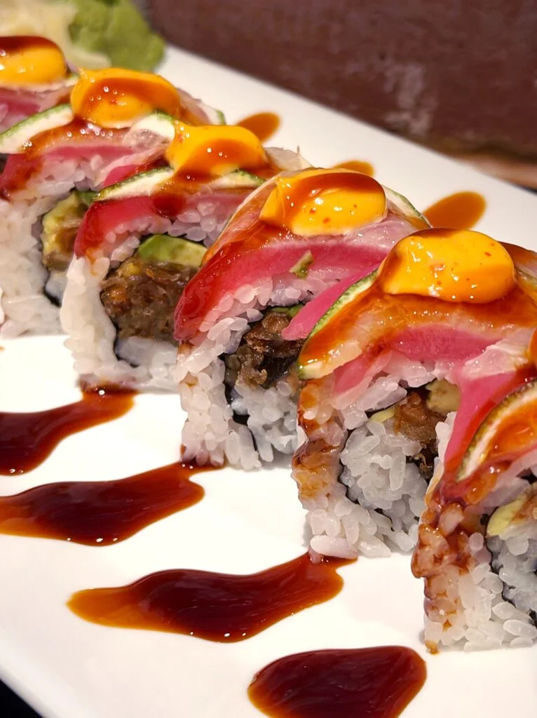 Colorful sushi roll with tuna and spicy sauce, served on a white plate