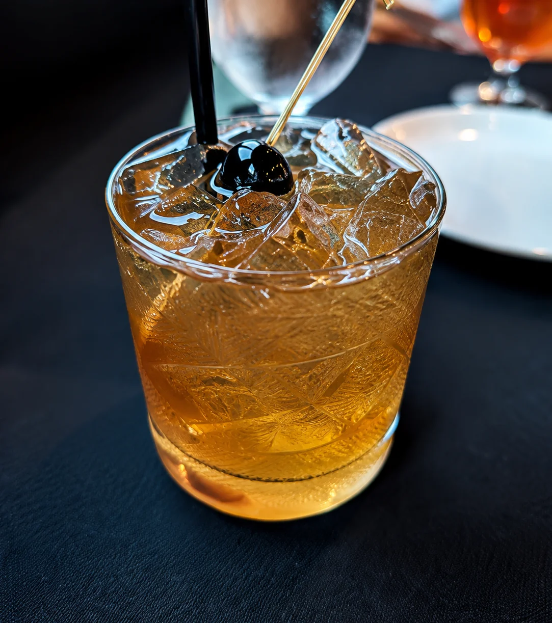 Classic whiskey cocktail served over ice with a cherry garnish