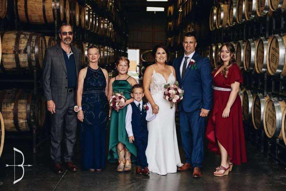 A wedding party smiling in a barrel rackhouse