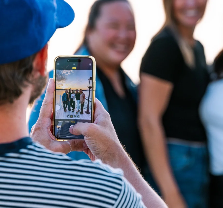Group of friends posing for a photo at sunset by the water