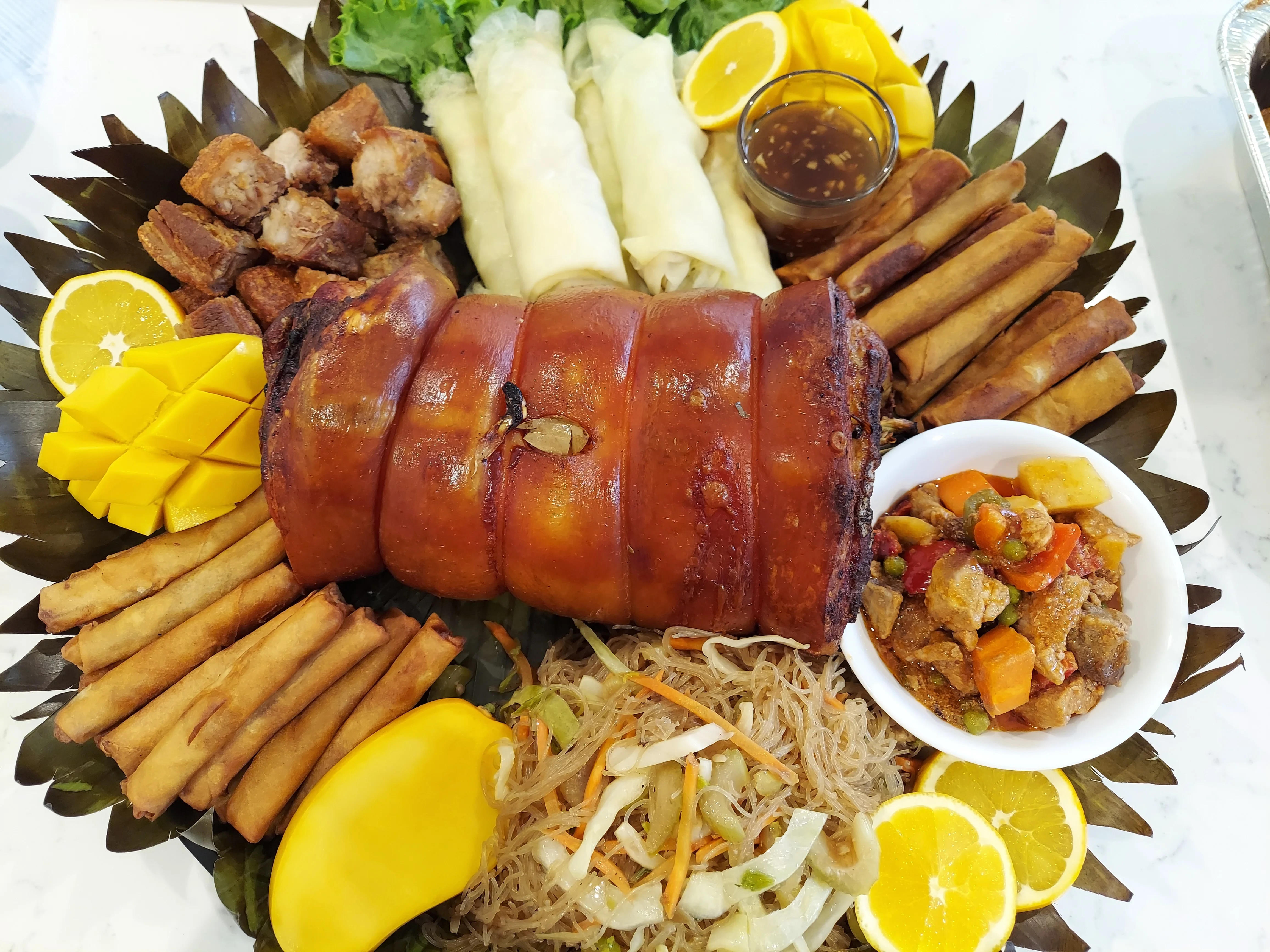 Filipino lechon with assorted side dishes and fresh fruits