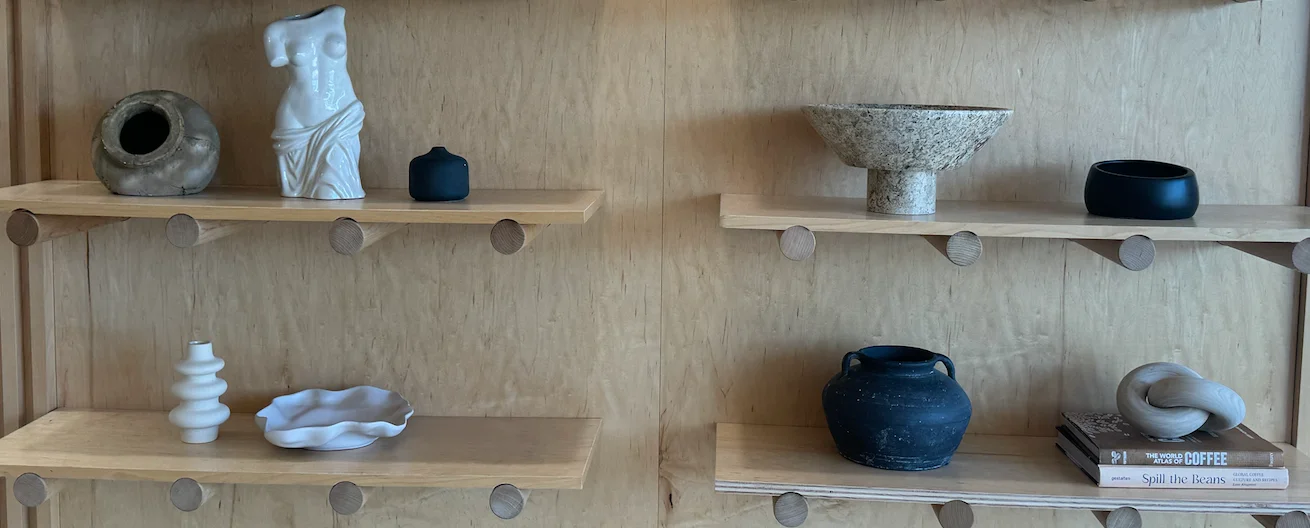 Artistic display of ceramic vases and sculptures on wooden shelves