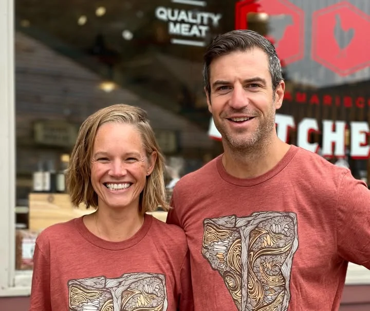 Couple wearing matching graphic t-shirts outside a butcher shop
