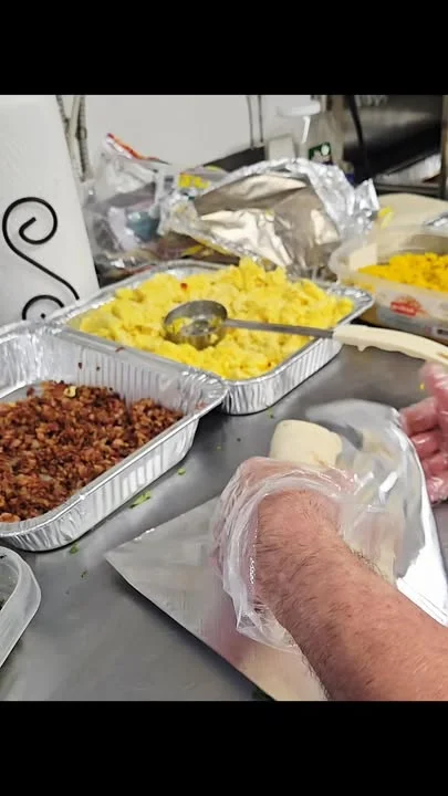 A close-up of hands preparing food in a kitchen, with various egg dishes and ingredients arranged on the table.