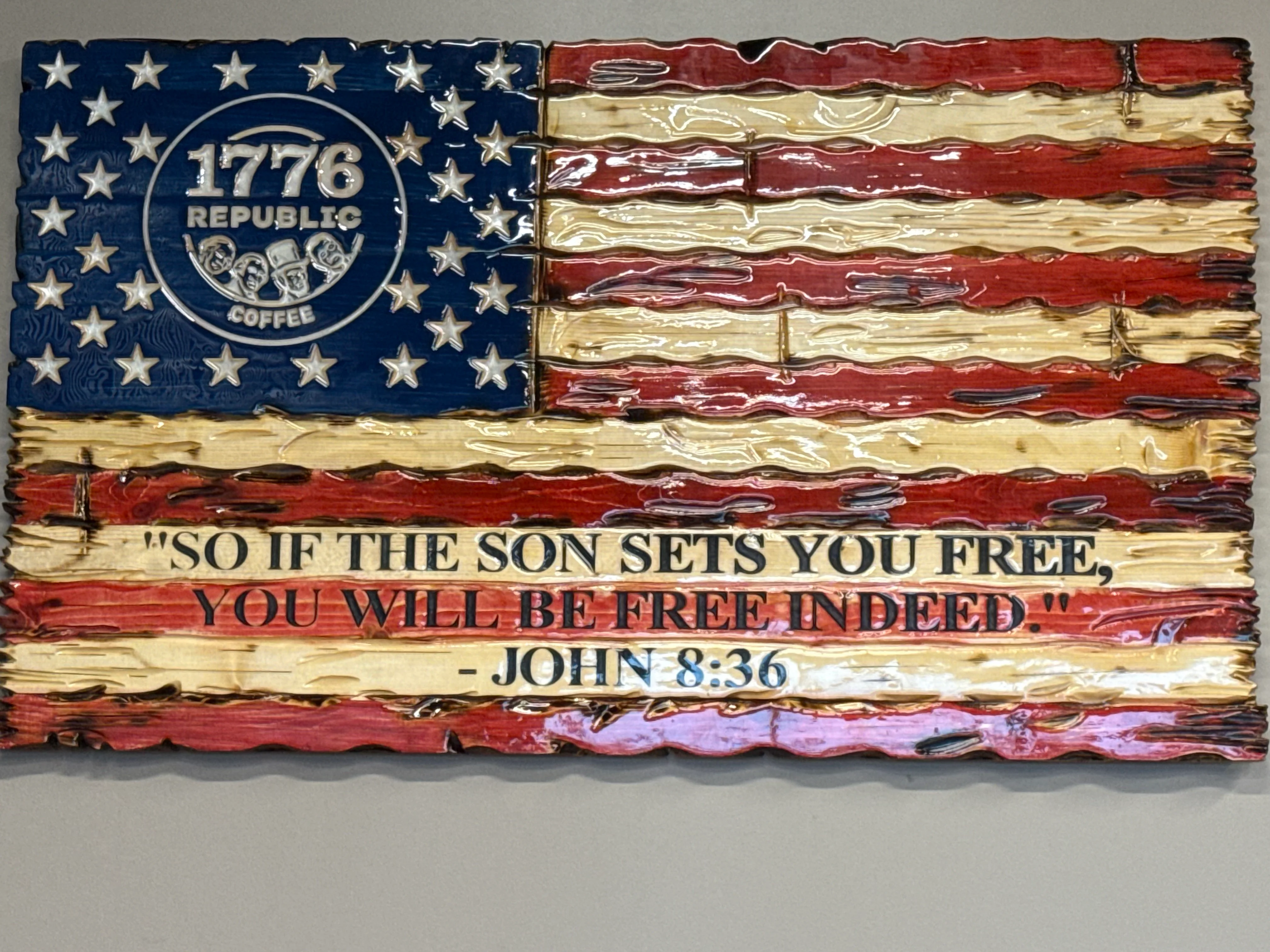 Wooden flag art with coffee brand and biblical quote on freedom.